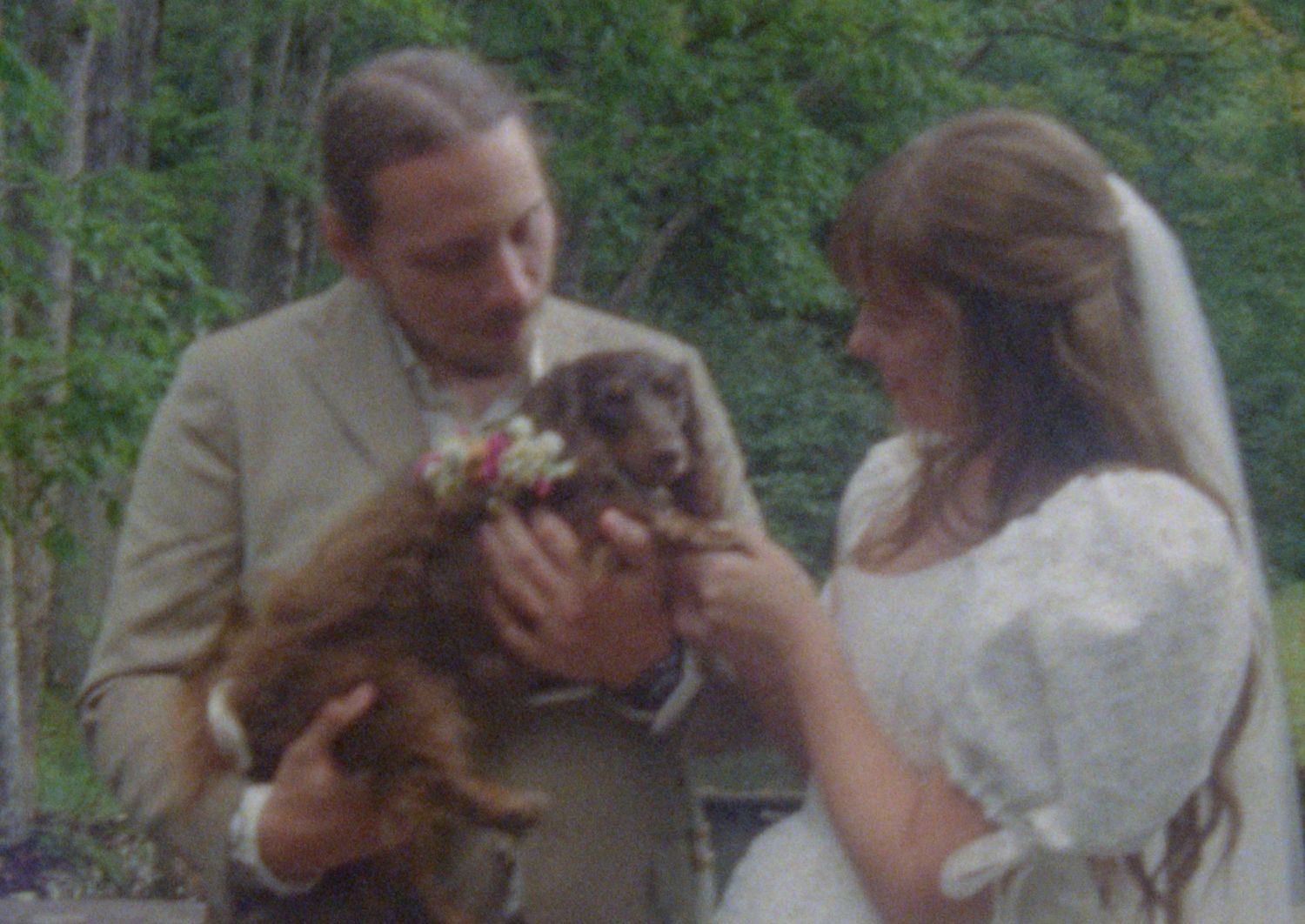 A couple shares a tender moment during their outdoor wedding ceremony in a wooded setting.