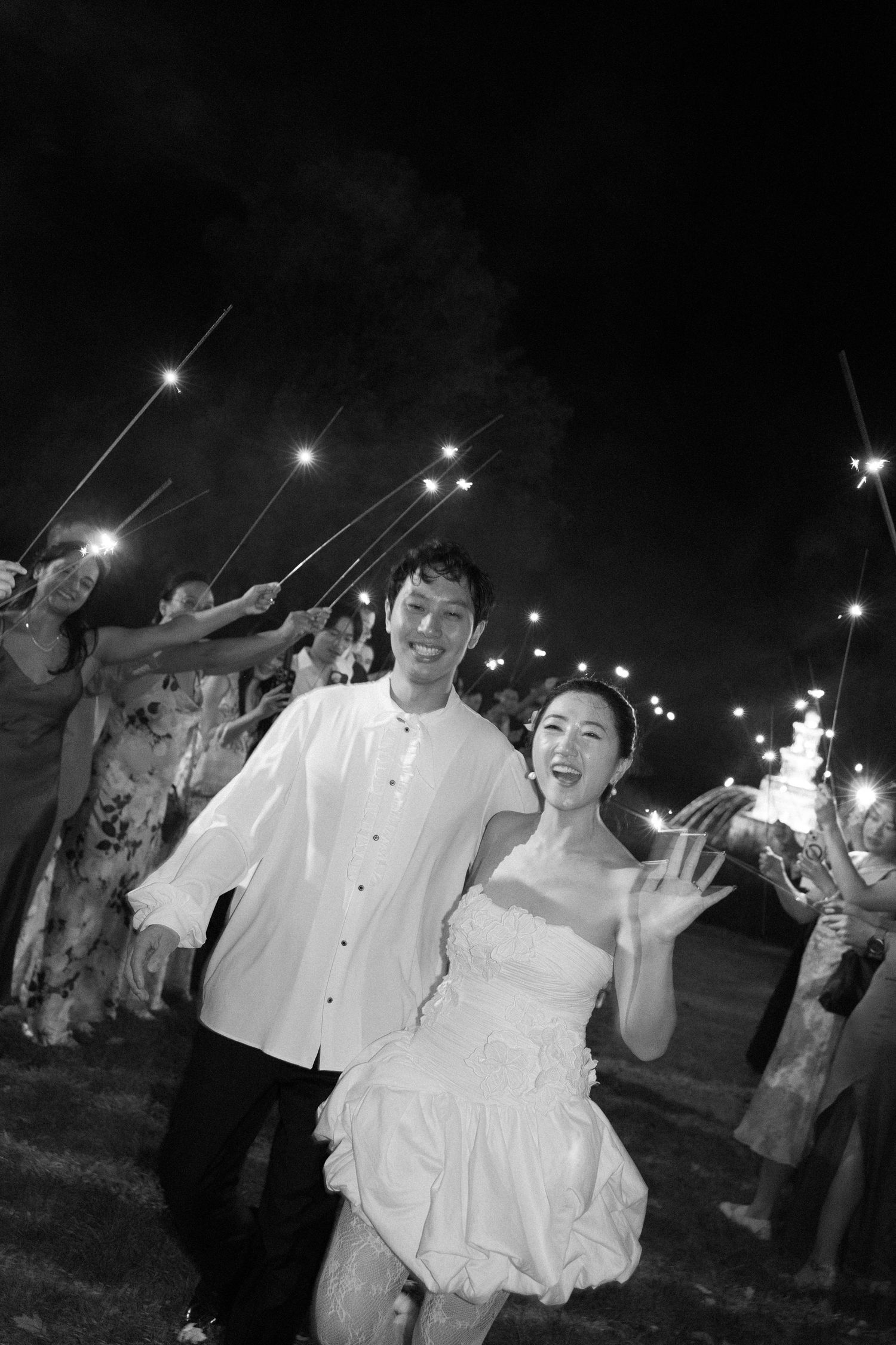 A wedding celebration at night with sparklers creating a magical glow as guests celebrate the newlyweds.