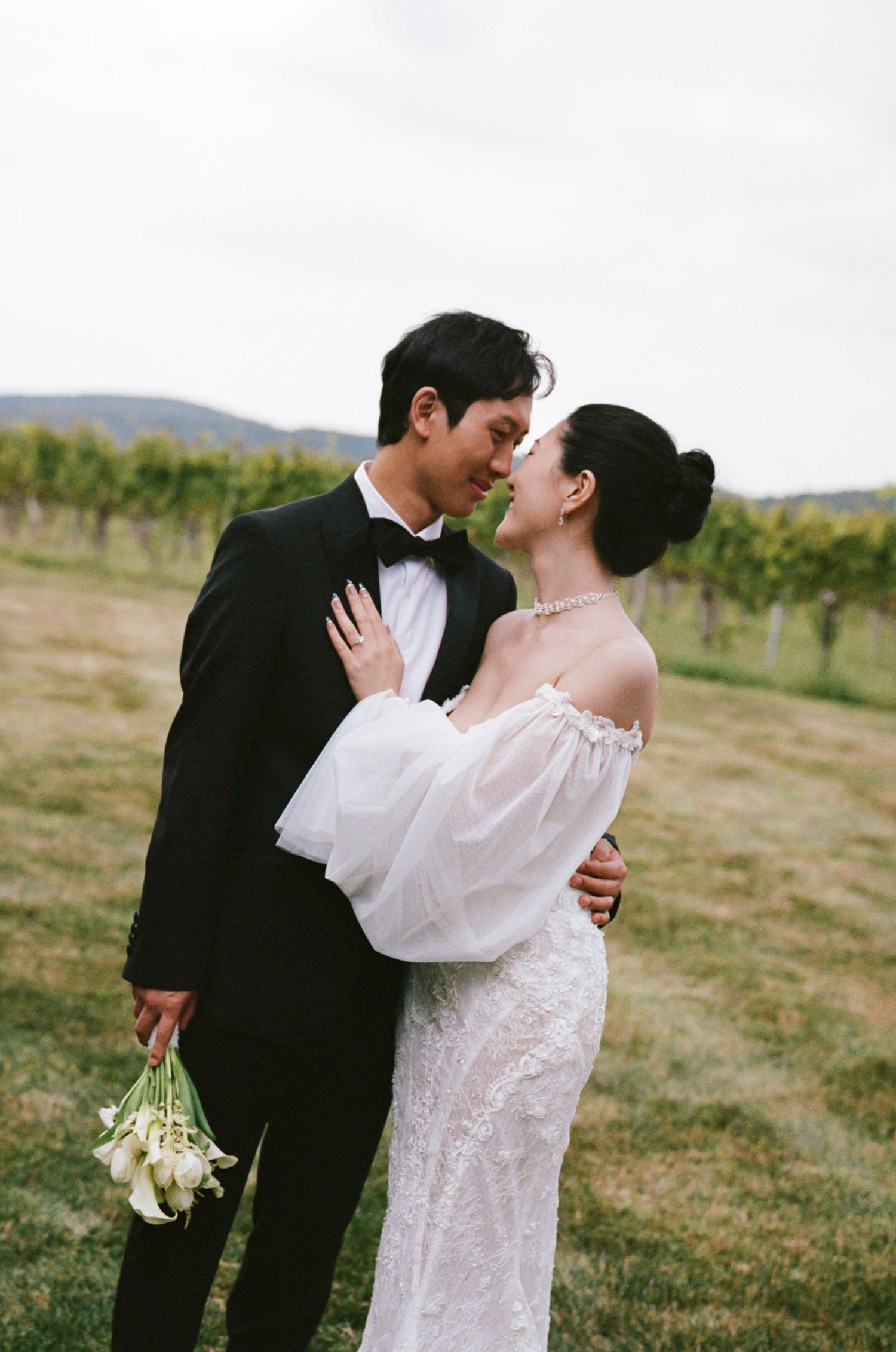 Romantic couple in wedding attire share intimate kisses in a scenic vineyard setting during their special day.