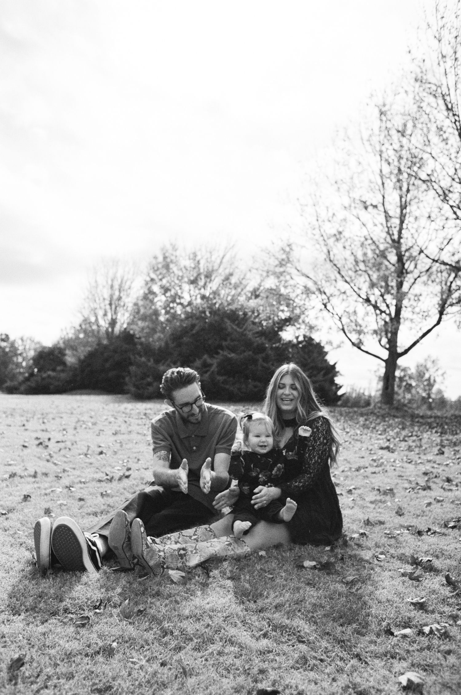 A family enjoys a casual moment together on a hillside during fall.