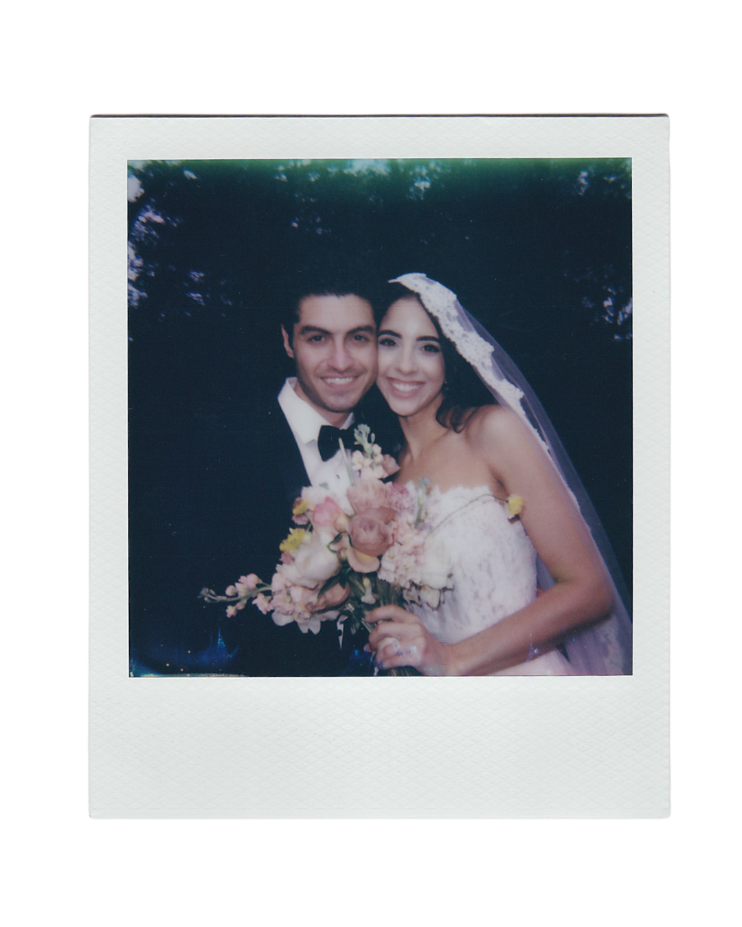 A vintage-style Polaroid wedding photo showing a happy couple in formal attire with a pink floral bouquet.