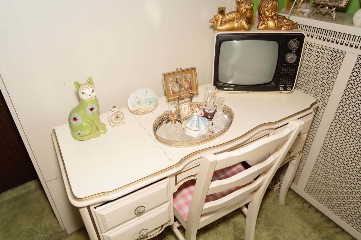 Vintage television set and antique furniture arranged in a retro-style room with decorative items.