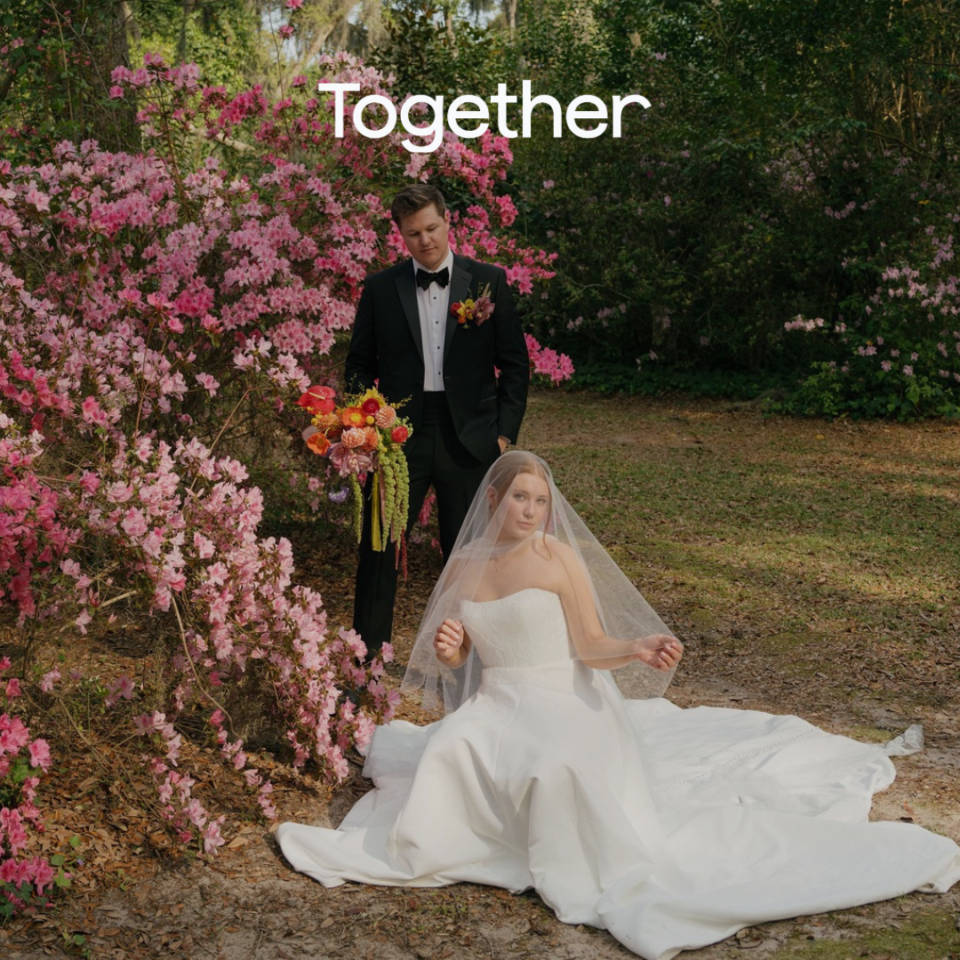 Bride in white gown sits on grass beside groom in tuxedo near blooming pink azaleas with Together text overlay.
