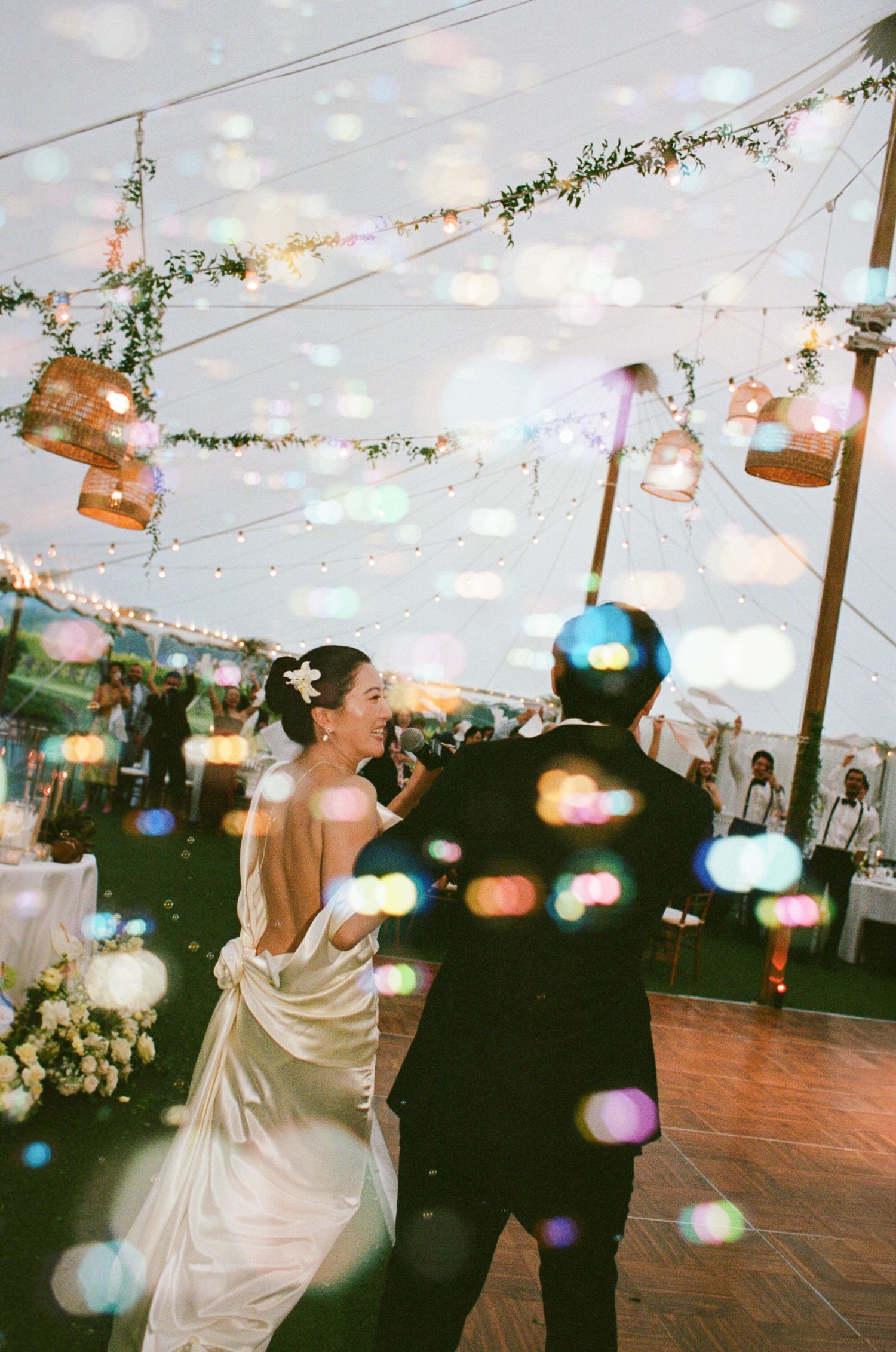 A romantic first dance sequence at a wedding reception under twinkling string lights and floral decorations.