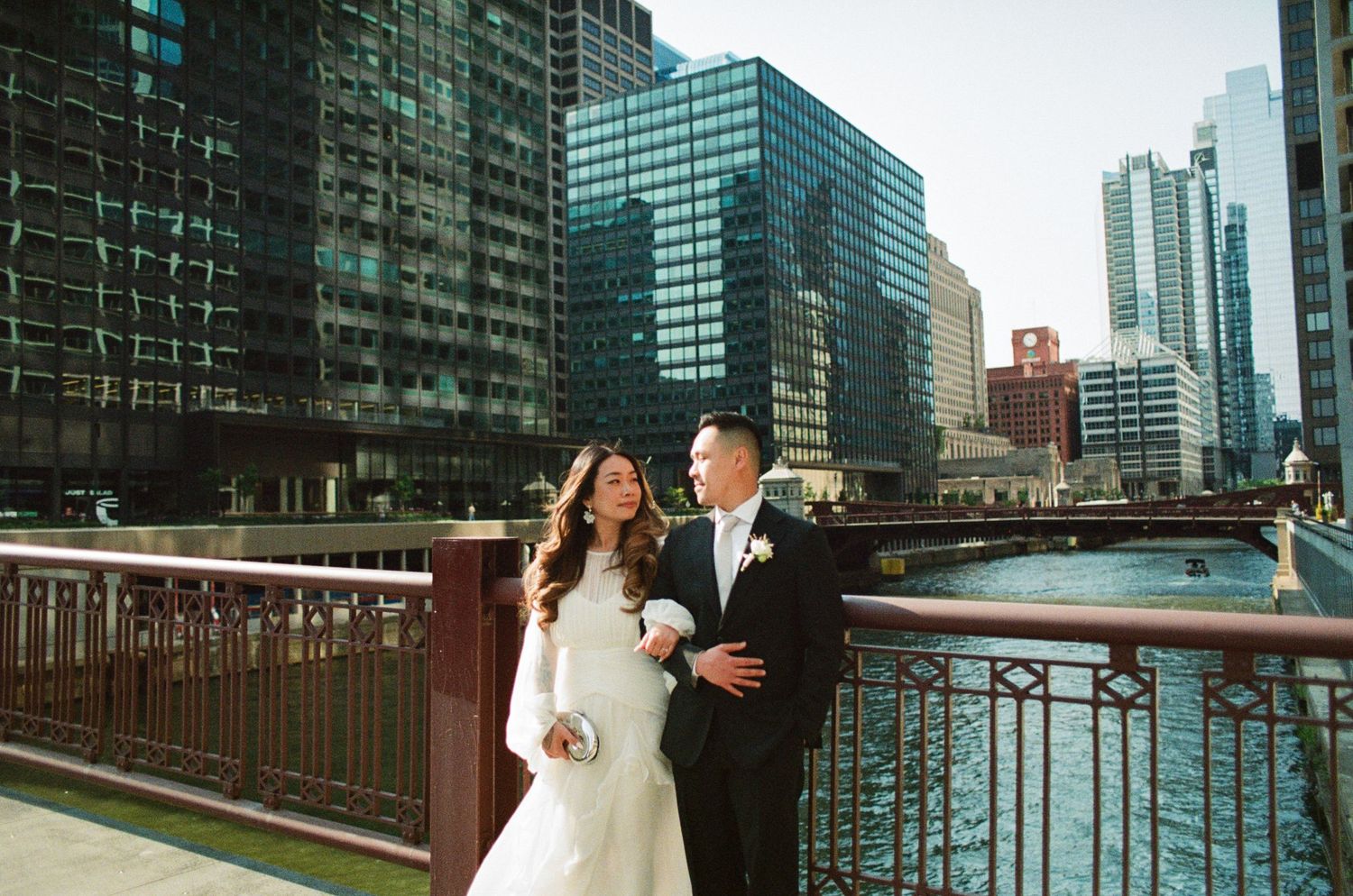 Wedding couple embraces on a city rooftop with modern glass skyscrapers and urban architecture in the background.