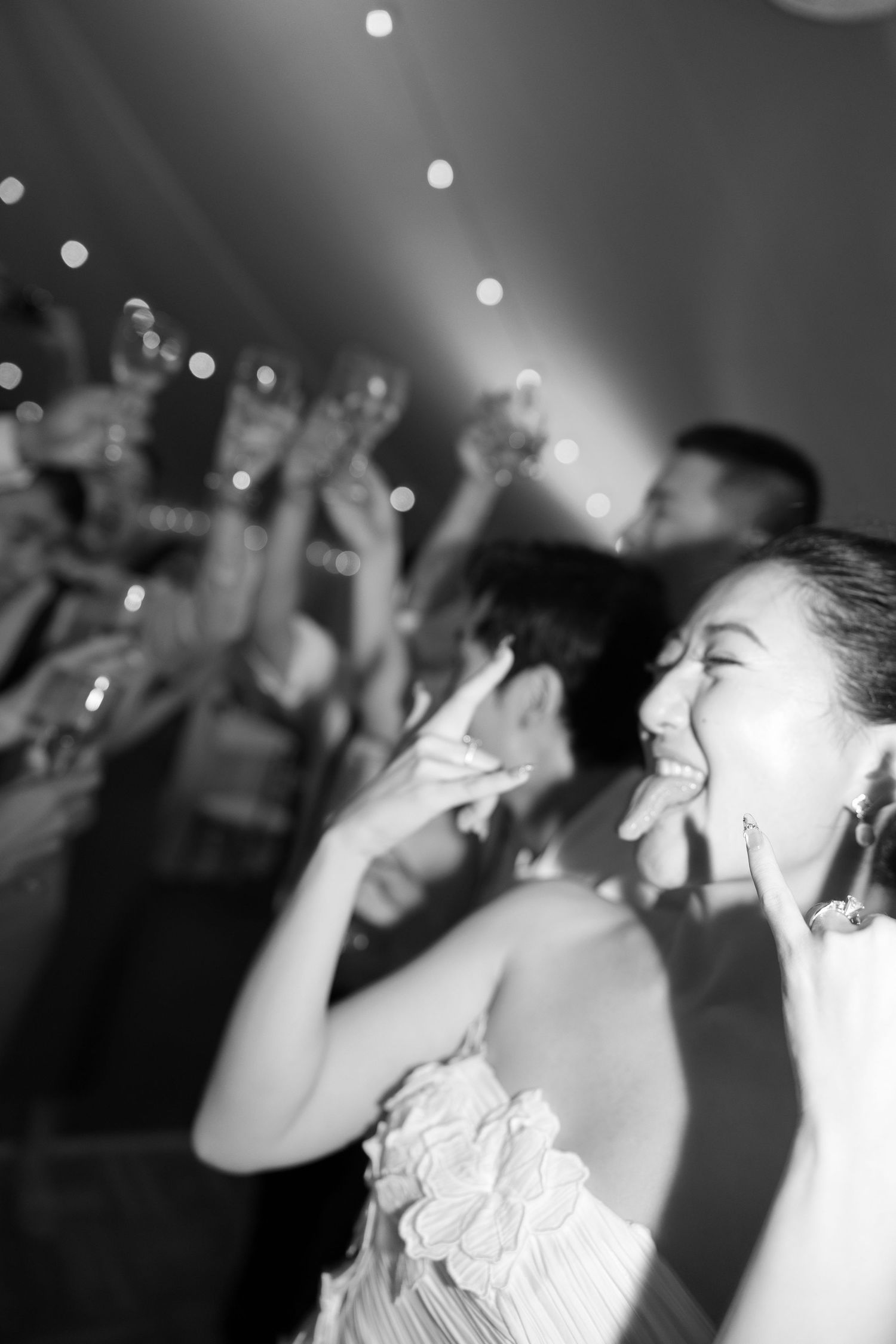 People dancing and celebrating at a nightclub or party with bokeh lights in the background.