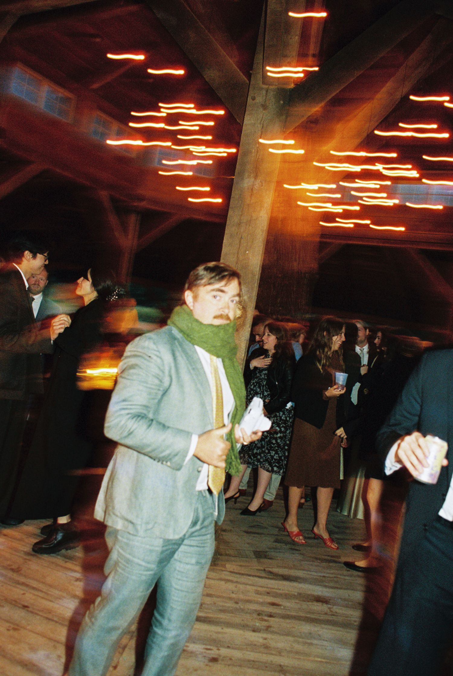 People dancing in a dimly lit venue with orange neon lights creating zigzag patterns on the ceiling.