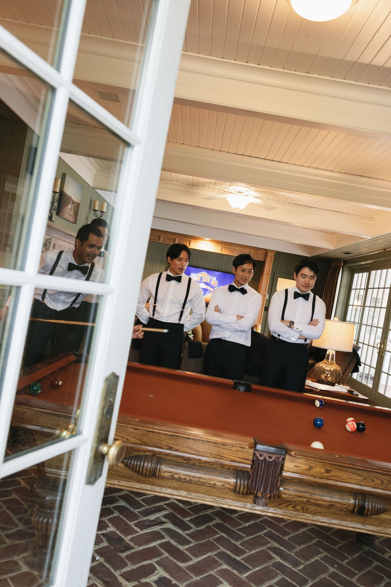 A group plays bocce ball on an indoor court with brick flooring and white pillars.