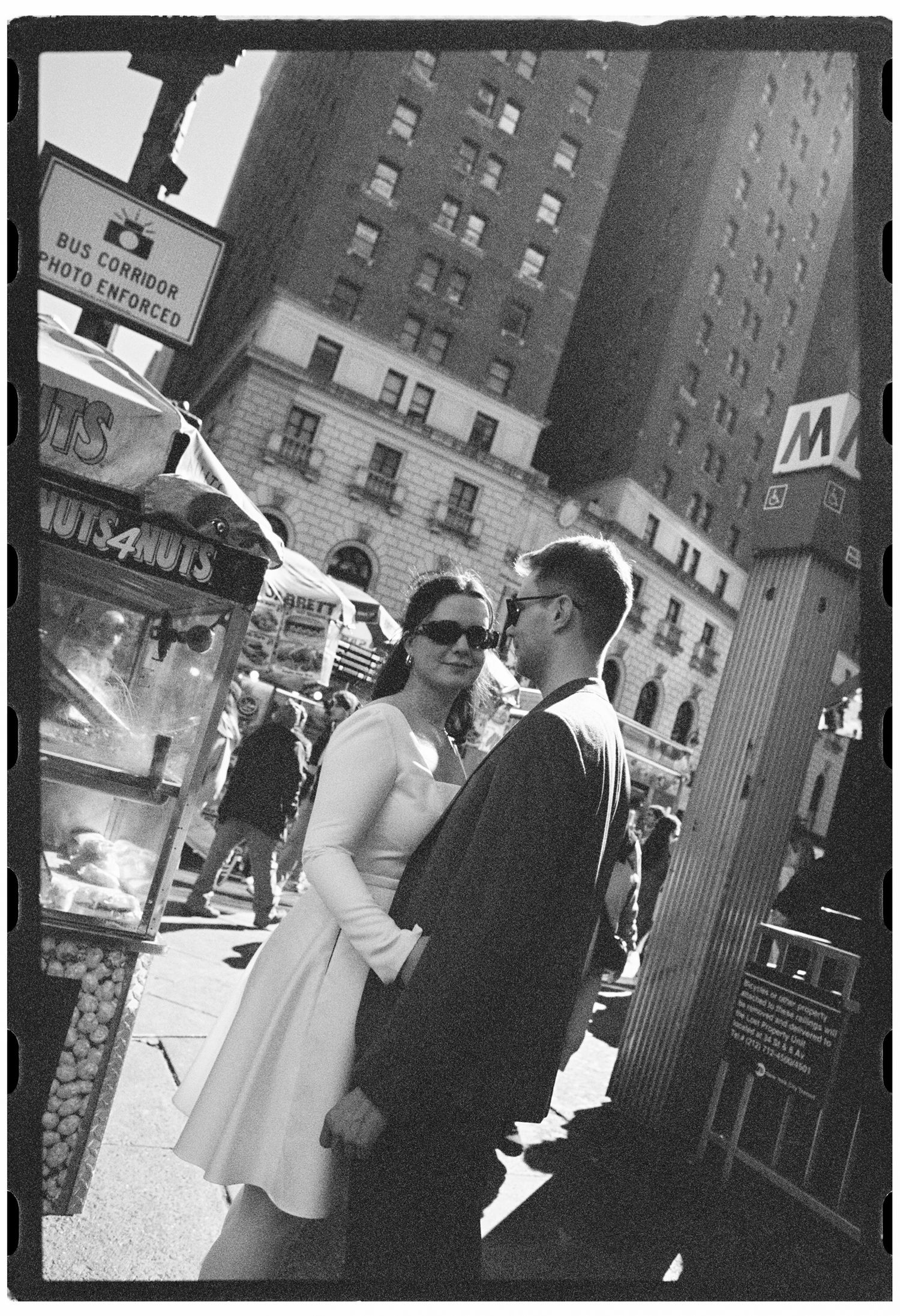 A vintage-style street scene with a couple in formal wear against city architecture.