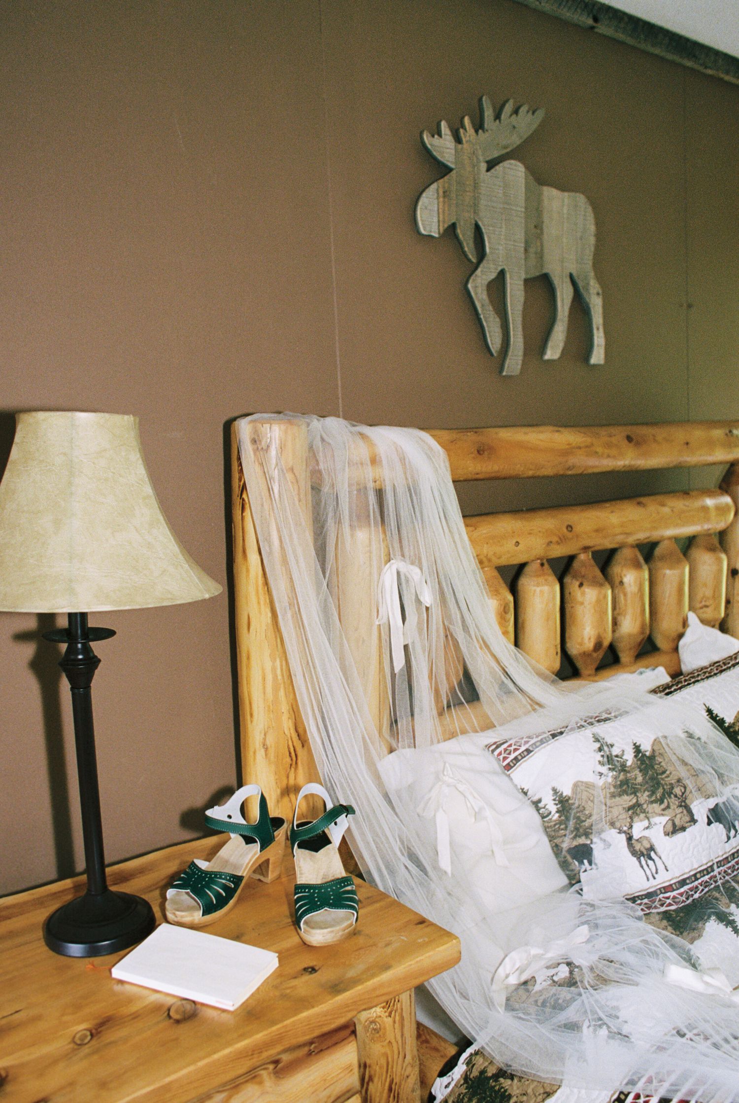 Rustic wooden headboard with decorative moose decor and table lamps in a cozy bedroom setting.