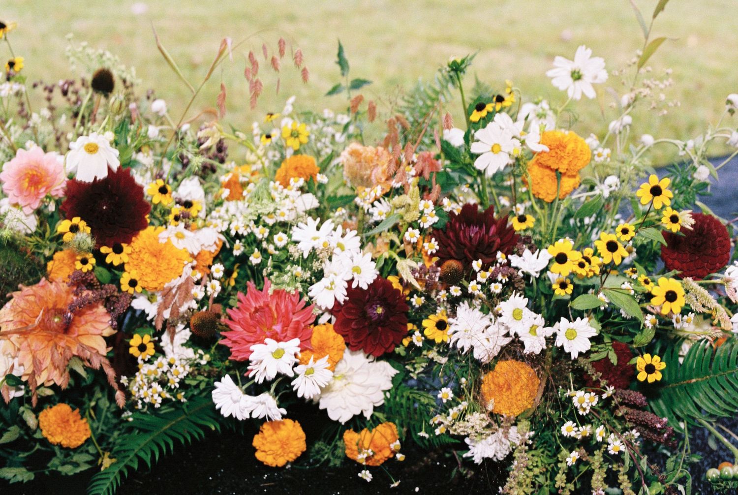 A colorful floral garland with orange, pink, and white flowers arranged against a light yellow background.