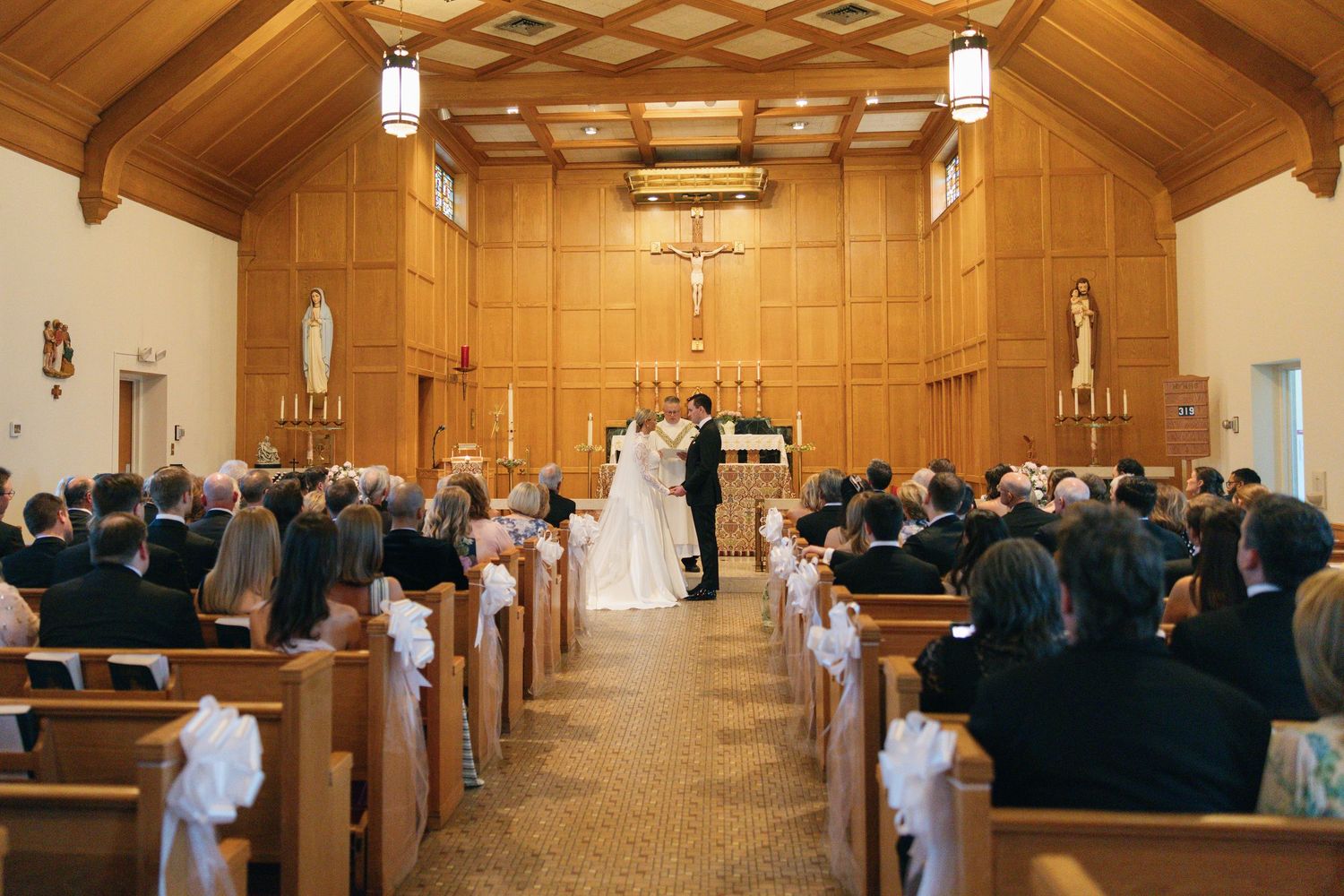 Bride and groom exchange vows at a traditional church wedding ceremony with guests seated in wooden pews.