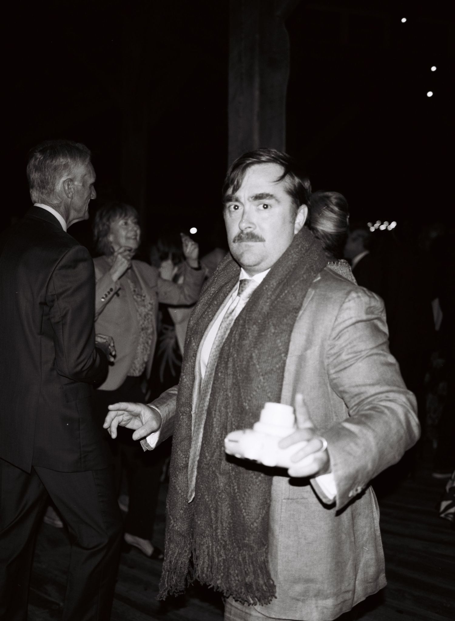 A series of black and white surveillance photos showing a person in a coat and scarf moving in the dark.