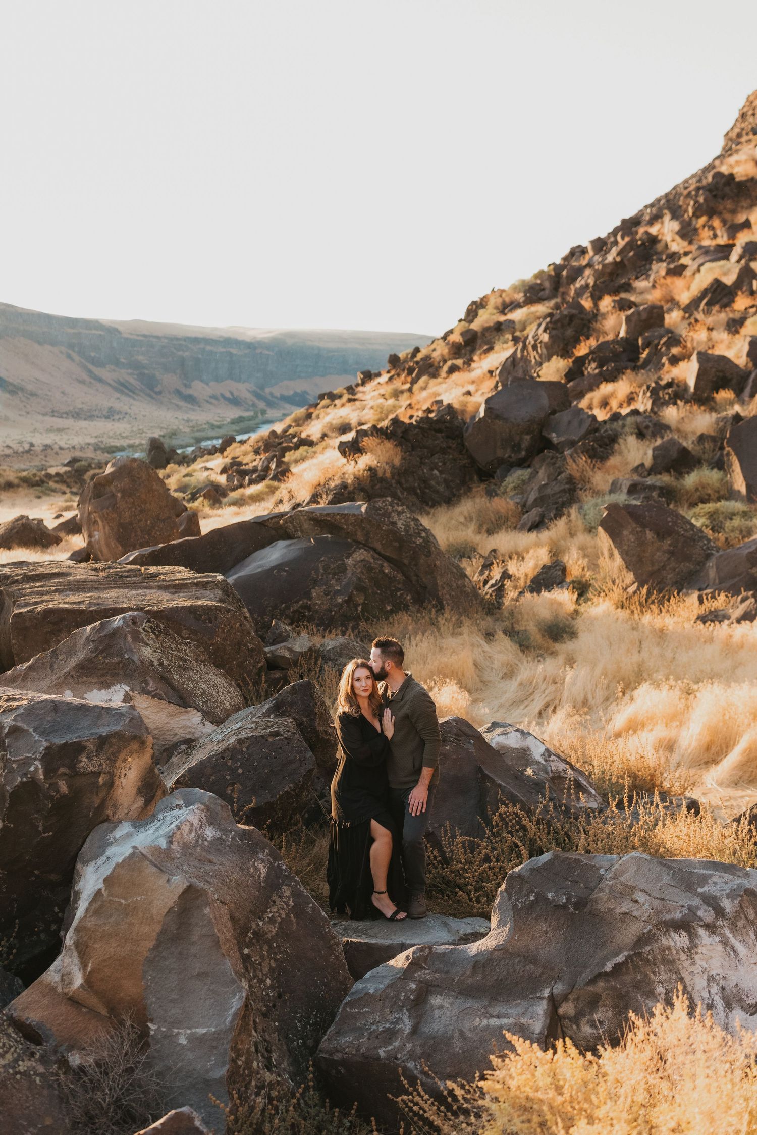 Silhouetted couple shares intimate moment among rocky outcrops in desert landscape during golden hour.