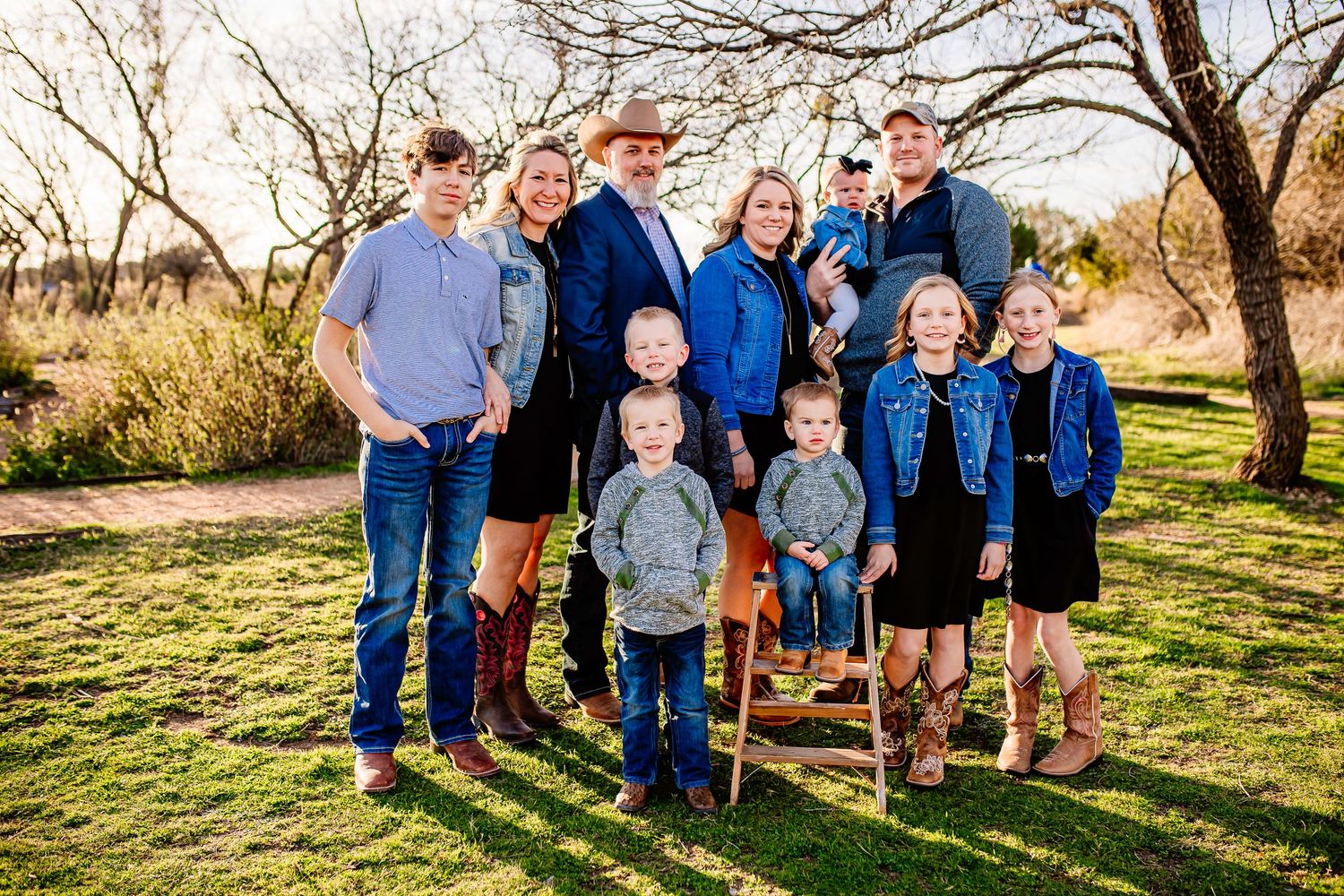 Family group posed together outdoors wearing coordinating blue and neutral clothing.