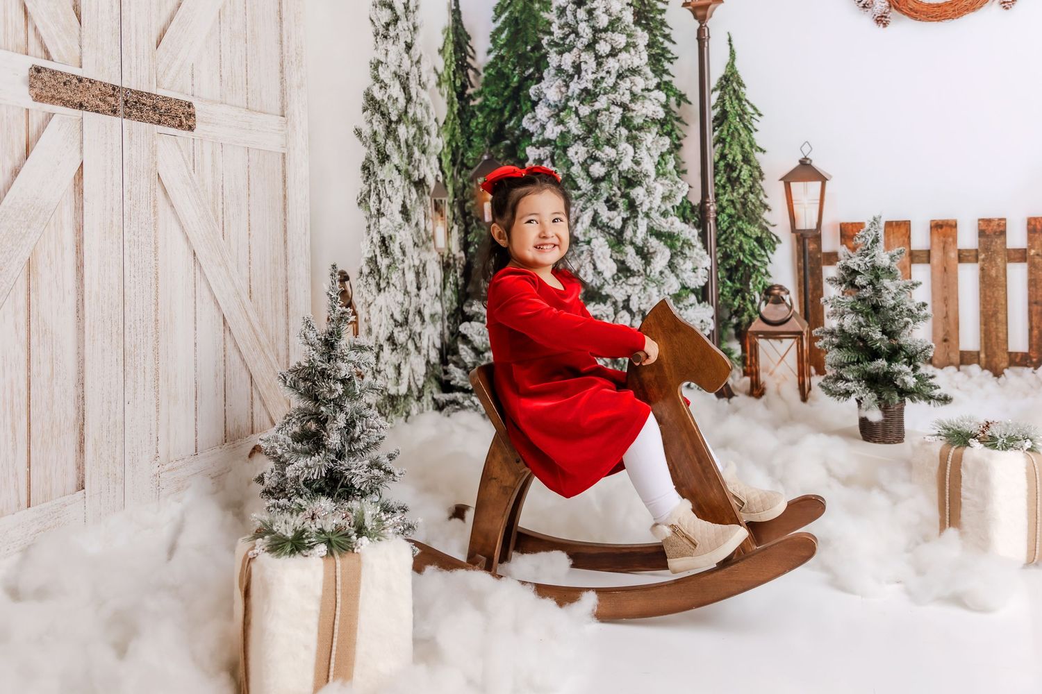 A cheerful winter scene with snow, wooden fencing, holiday lanterns and festive decorative elements in a portrait setup.