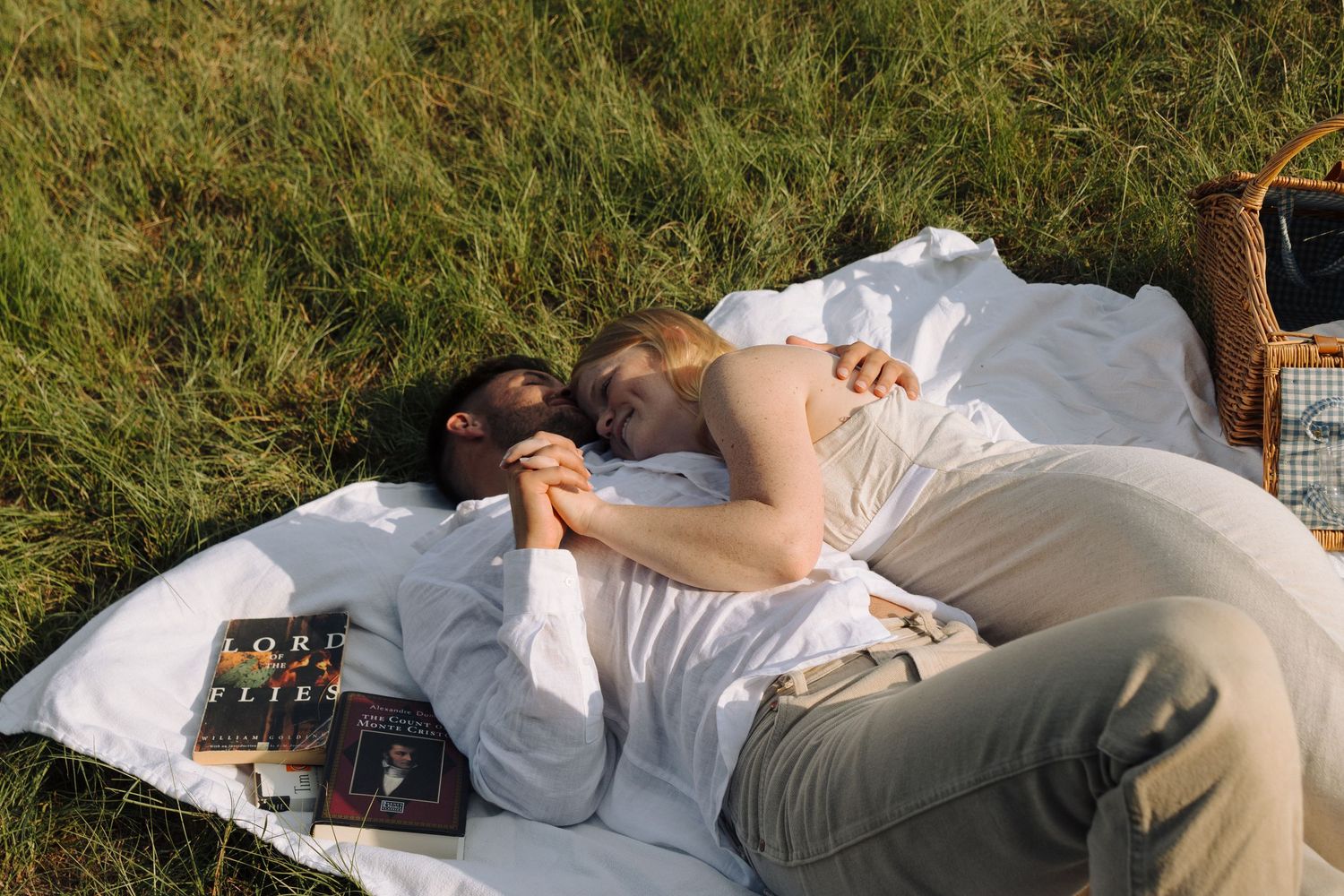 A person lies on grass in a relaxed pose during a sunny day outdoors.