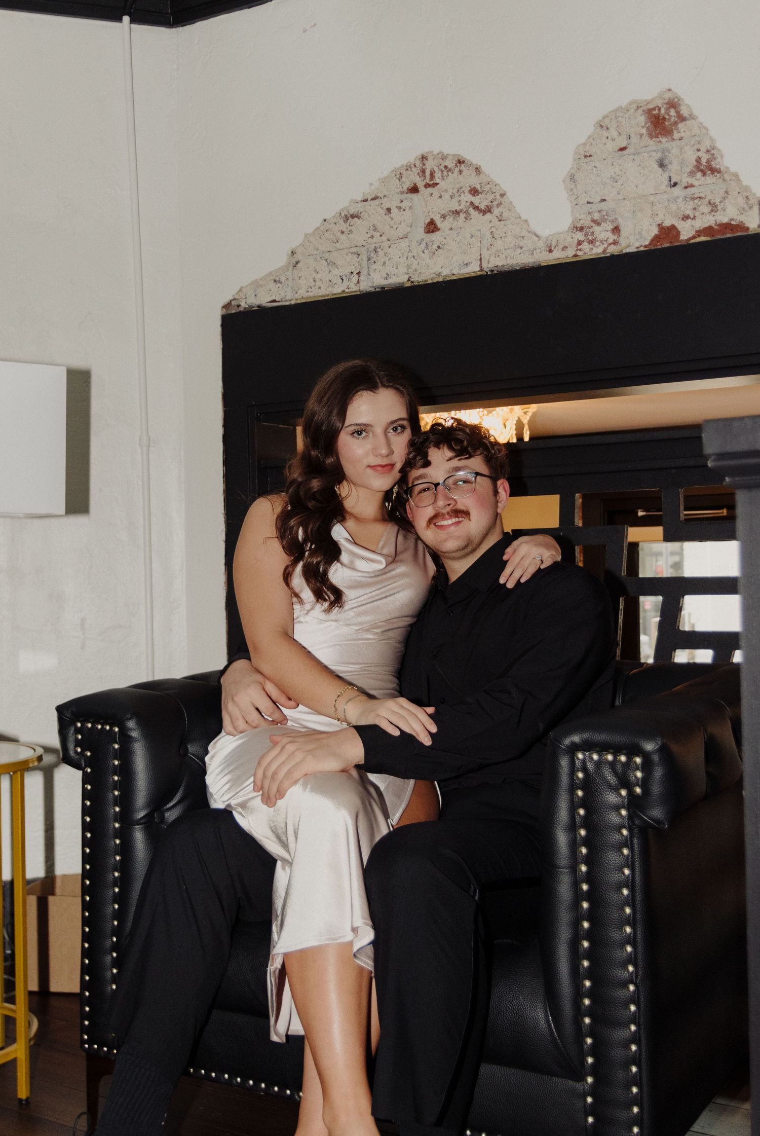 Black leather couch against white wall in a minimalist interior space with a couple in retro fashion.