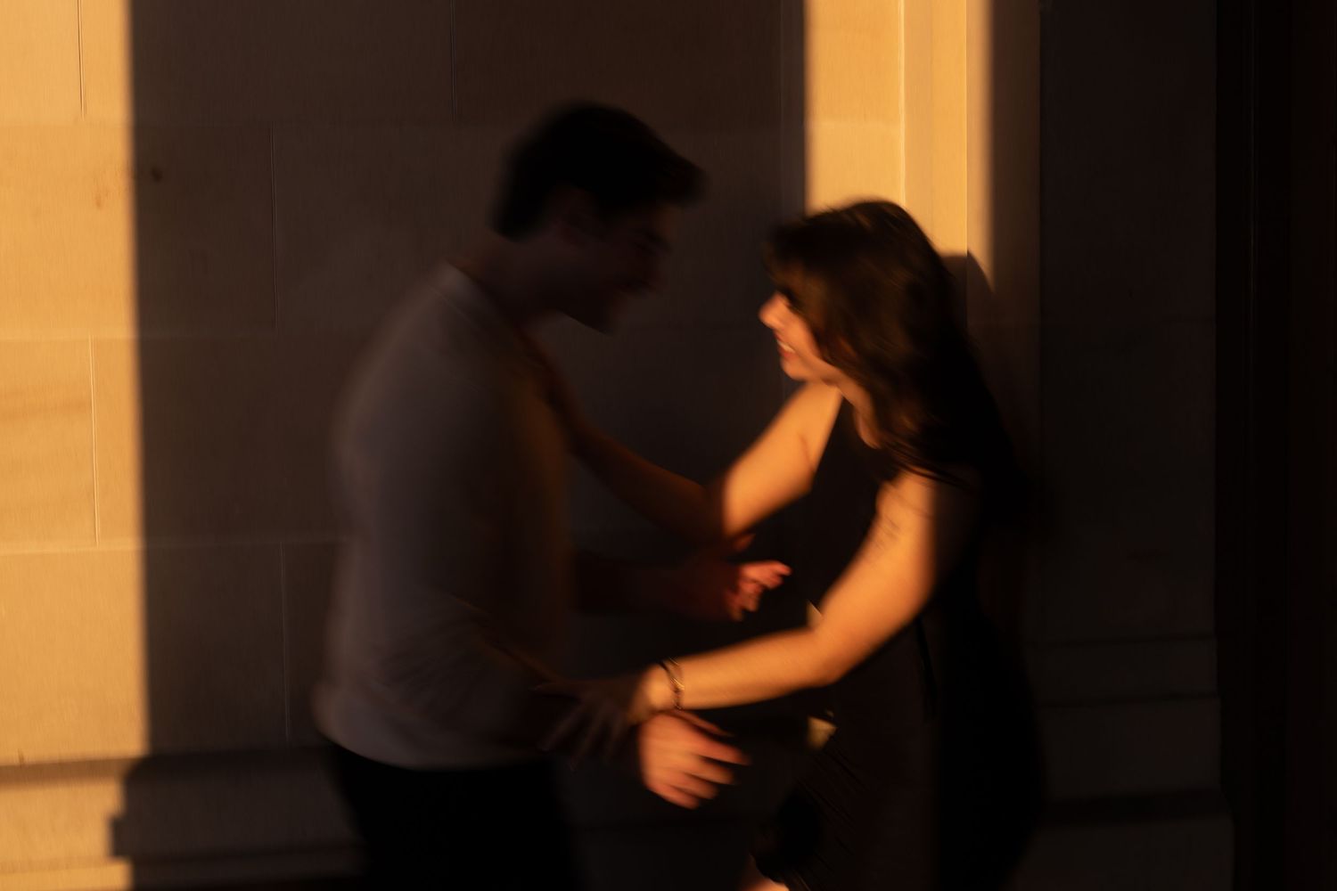 A couple performs an elegant dance move together in a dimly lit ballroom setting.