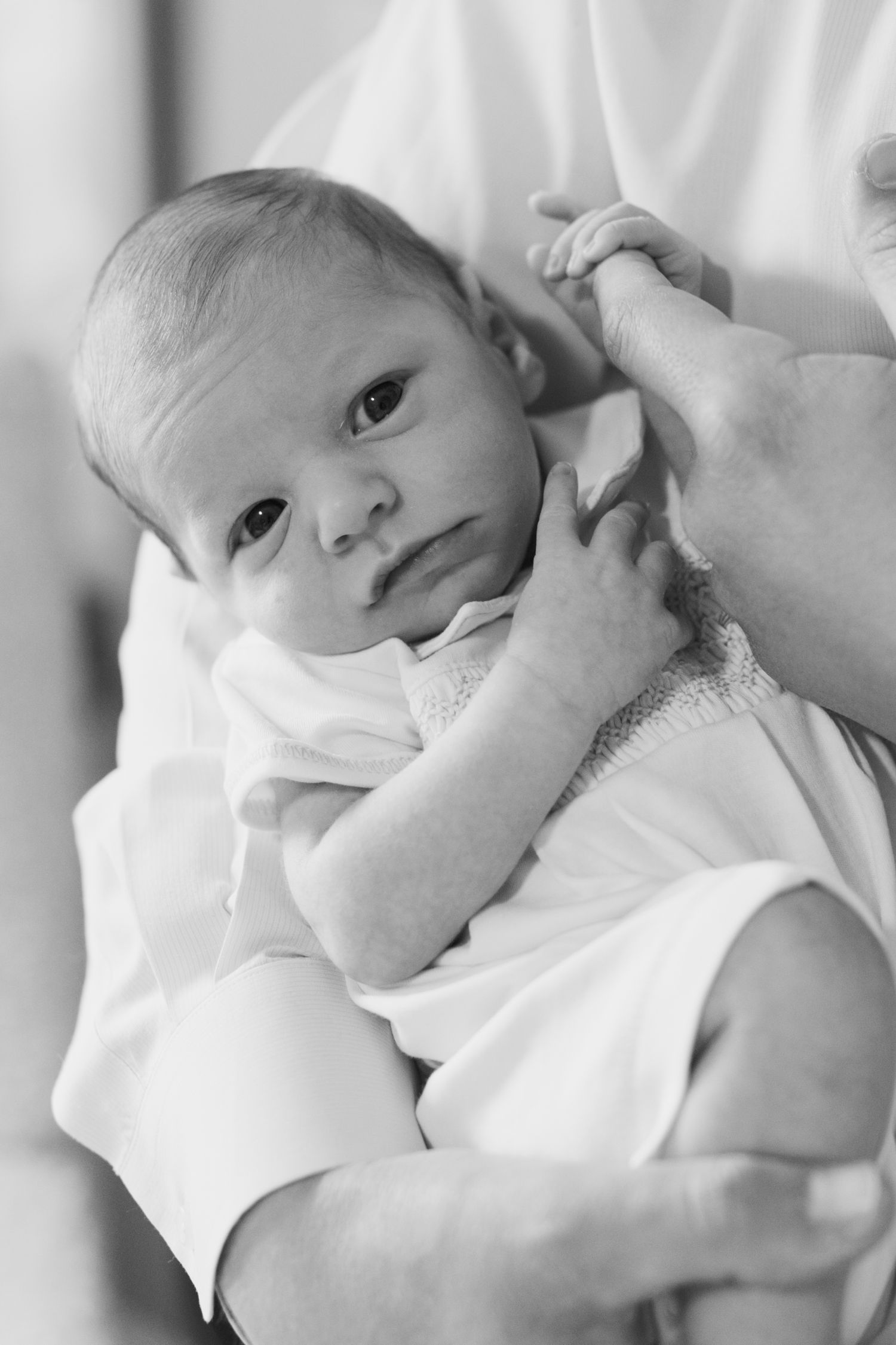 Newborn baby cuddled by parents during in-home photography session