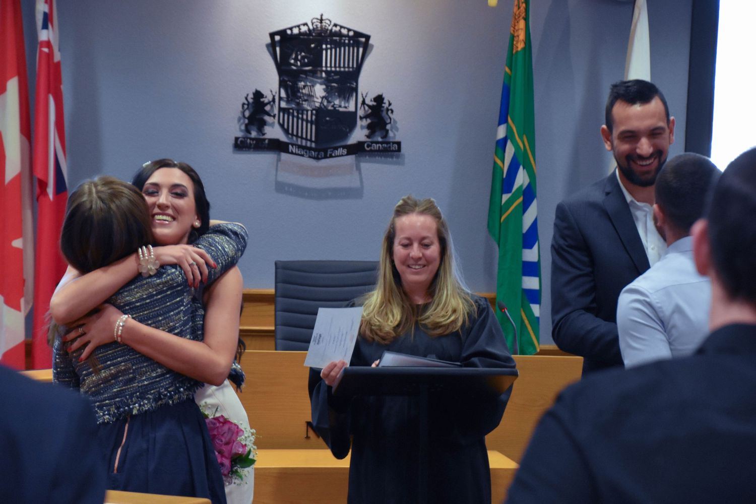 Couple and their friends celebrating at the end of a City Hall wedding in Niagara Falls council chambers.