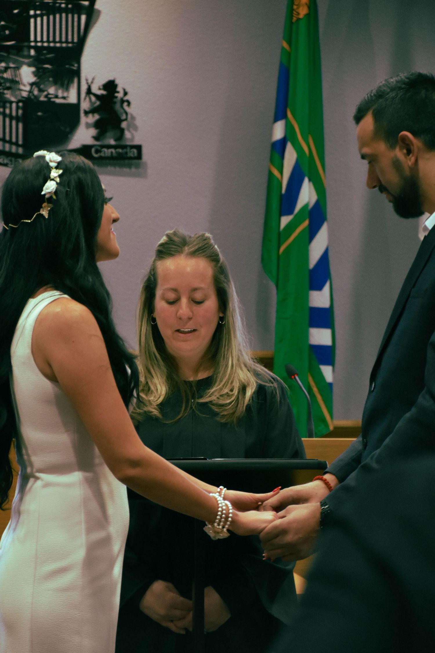 Couple exchanging vow during wedding ceremony in council chambers in Niagara Falls