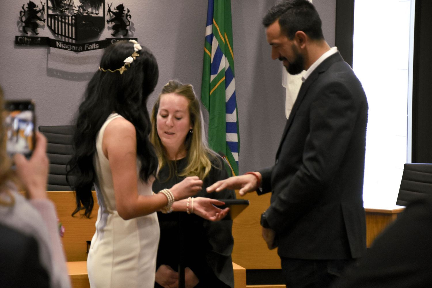 Bride and groom exchanging rings during wedding ceremony in council chambers at Niagara Falls City Hall.