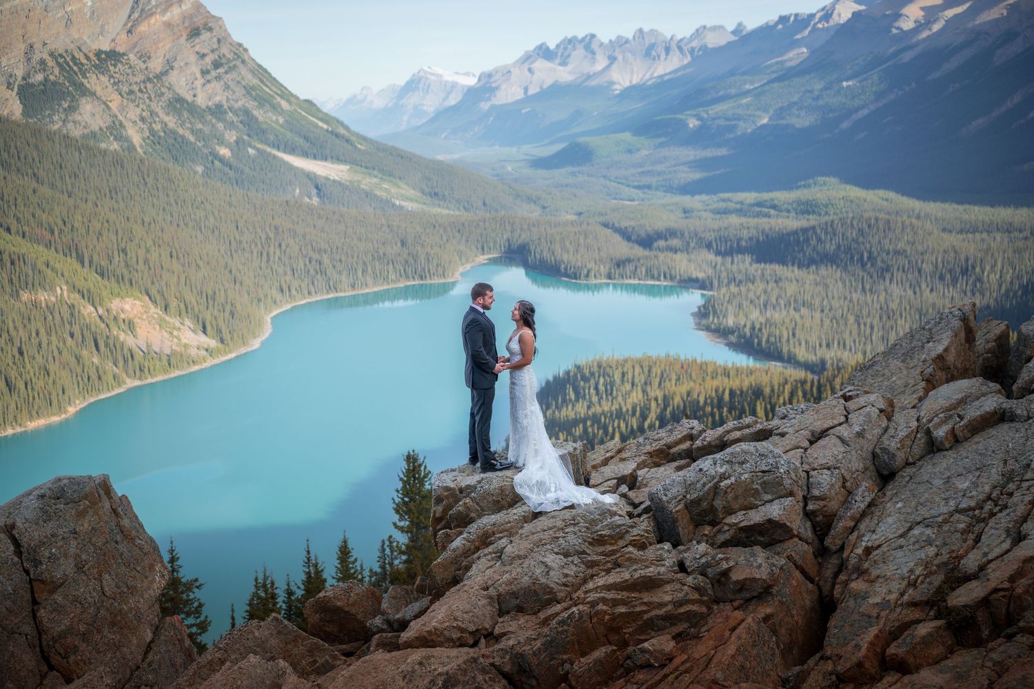 Couple exchanging vows on rocky mountain overlook above turquoise Peyto Lake, Banff National Park, Canada.