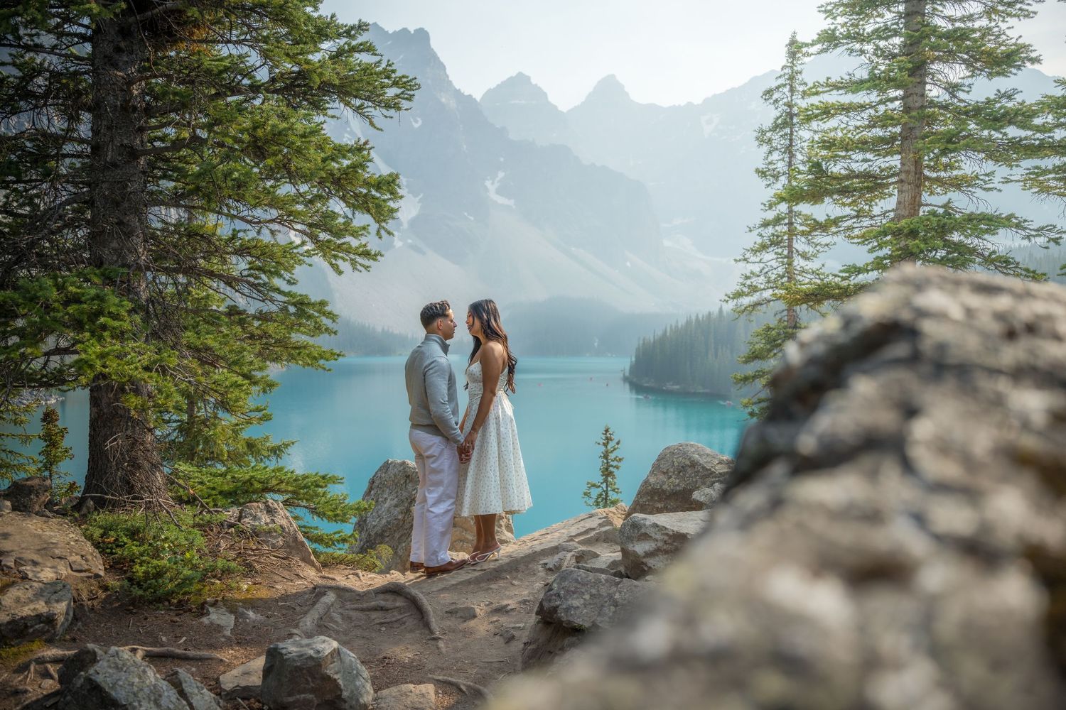 Couple exchanging vows at Moraine Lake, Banff, with turquoise water and misty mountains in background.