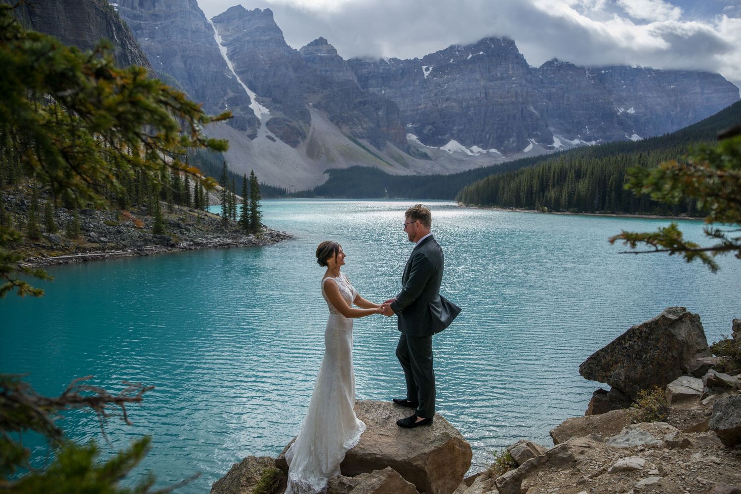 Couple exchanges vows at Moraine Lake, Banff, with turquoise water and Rocky Mountains backdrop.