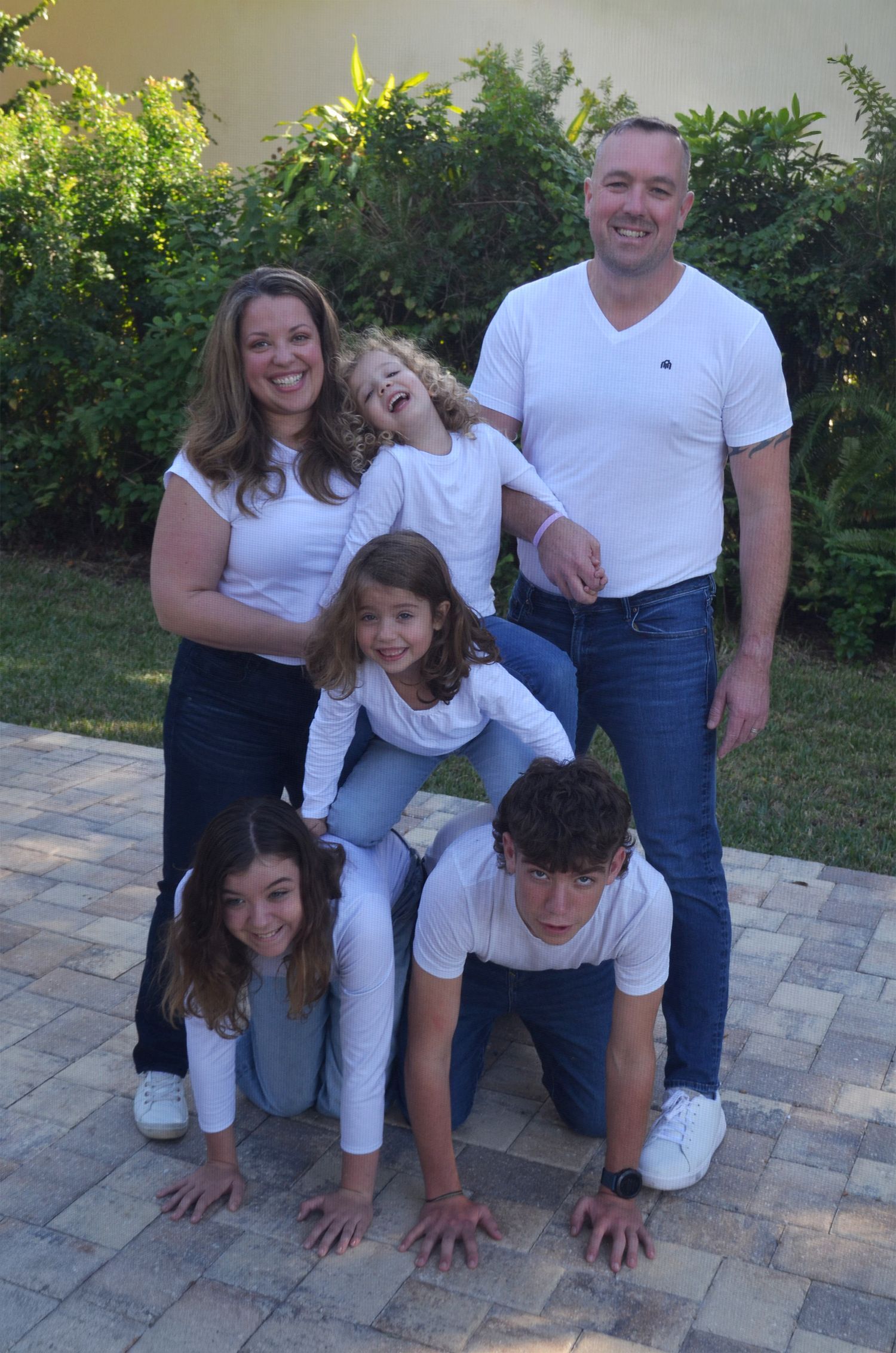 Family of six forming a human pyramid outdoors.