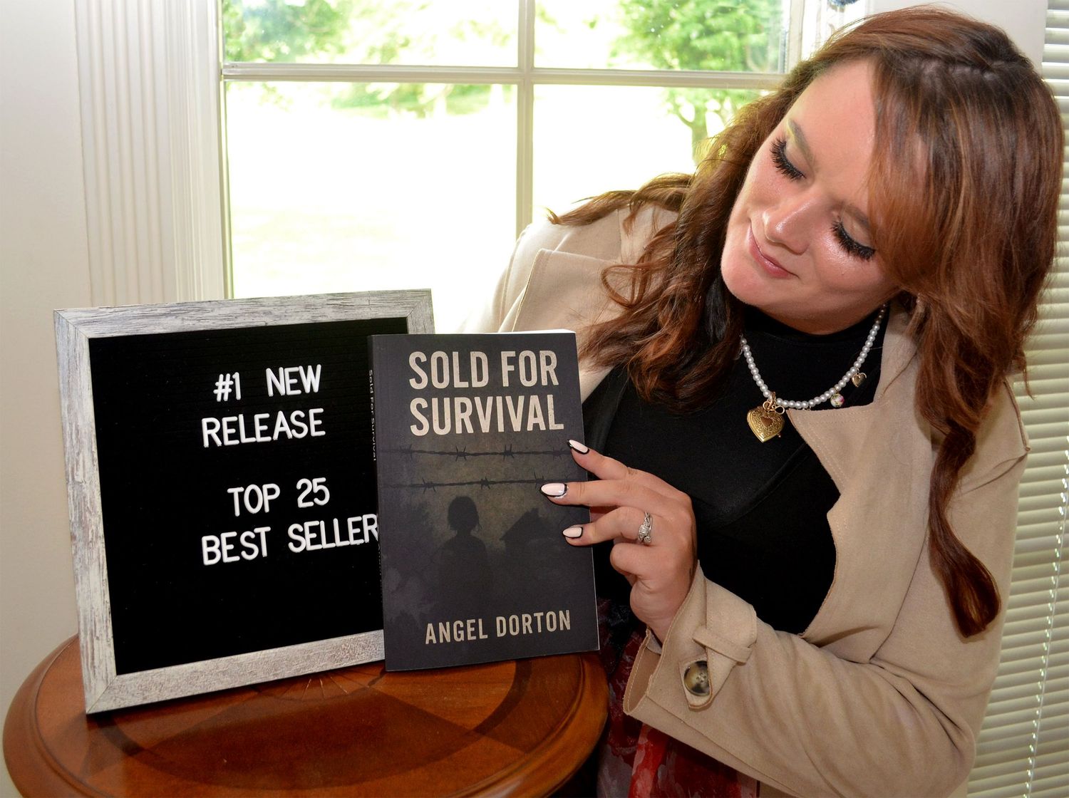 Author holding bestseller book beside award sign.