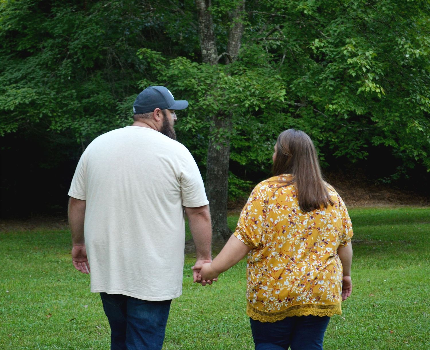 Couple holding hands walking through lush greenery taking a moment to themselves.