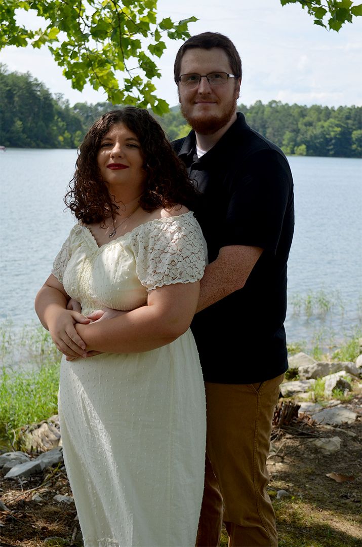 Couple embracing by a lake outdoors.