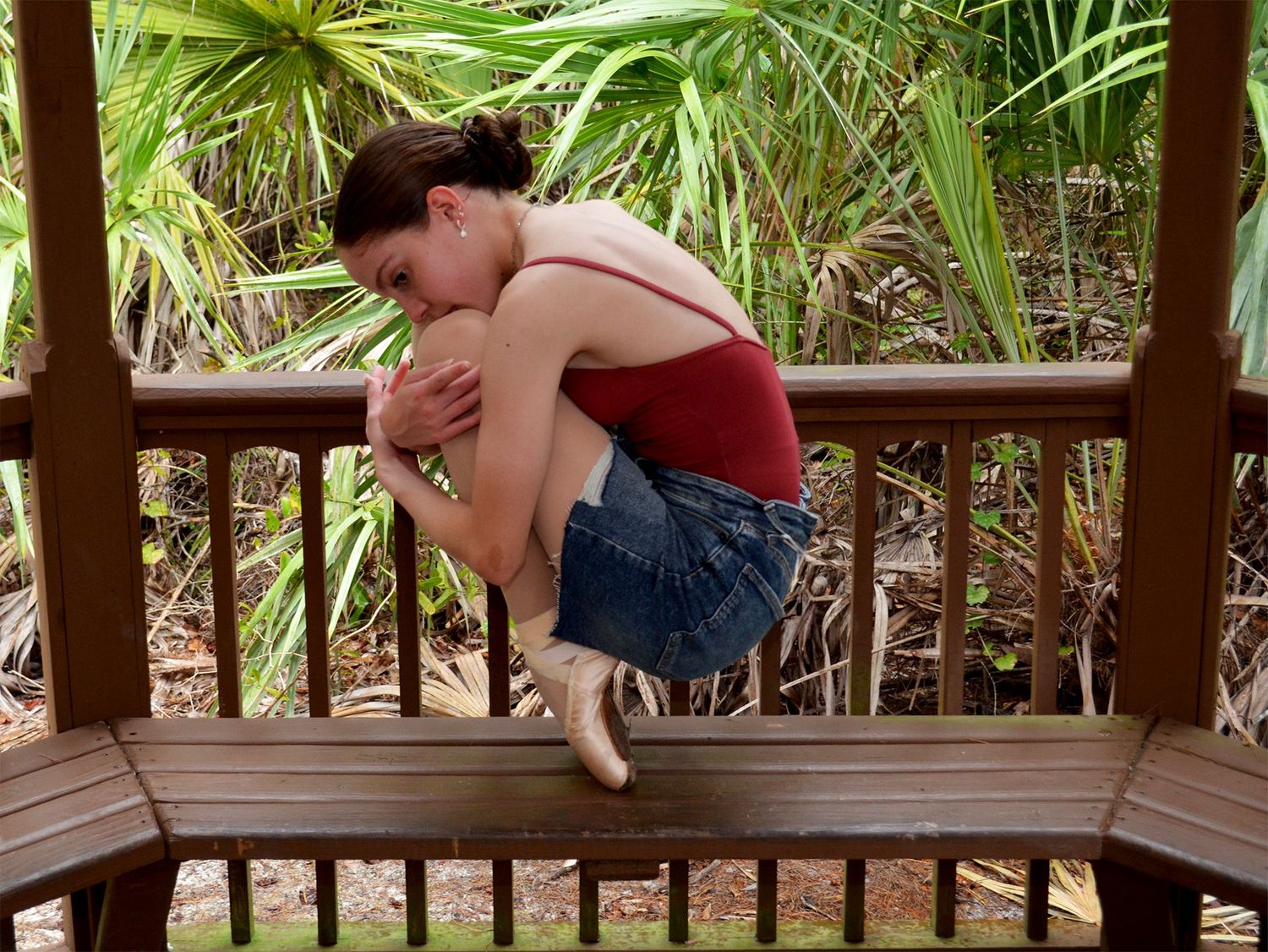 Ballet dancer balancing on gazebo railing.