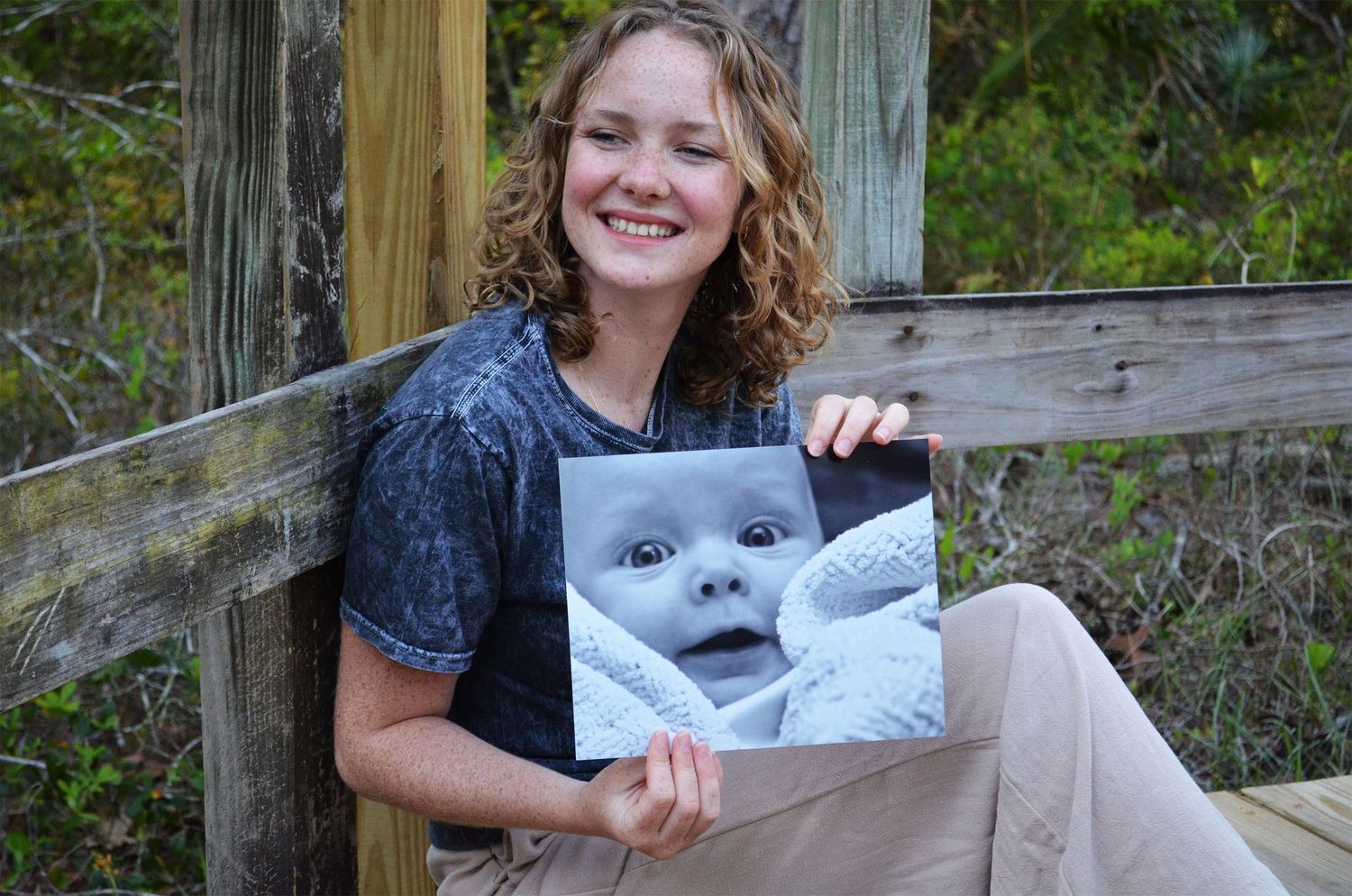 Teenage girl holding a baby portrait photo outdoors.