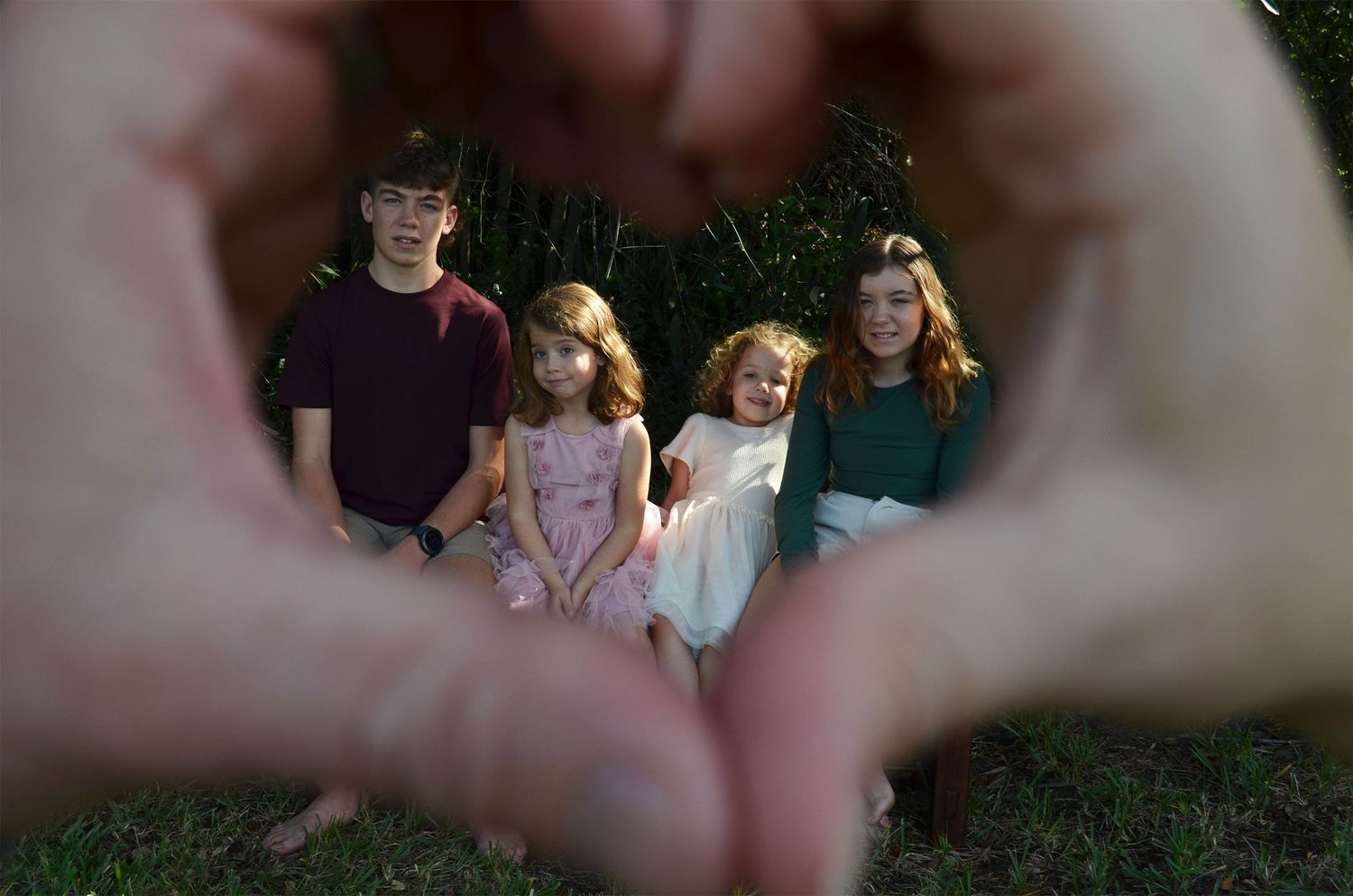 Four children posing with heart-shaped hands framing face.