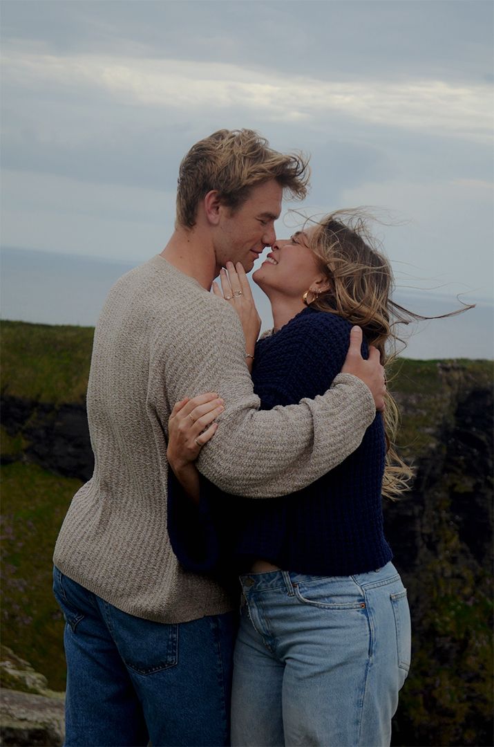 Couple sharing romantic moment on coastal cliffs.