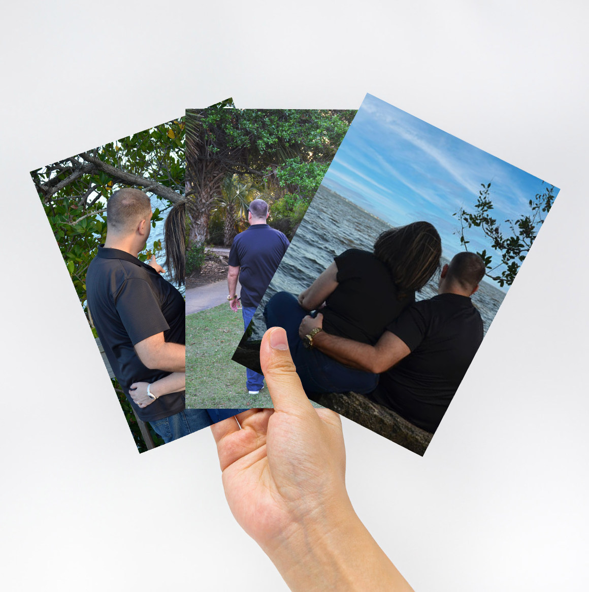 Hand holding three printed photos featuring a couple enjoying outdoor moments in nature.