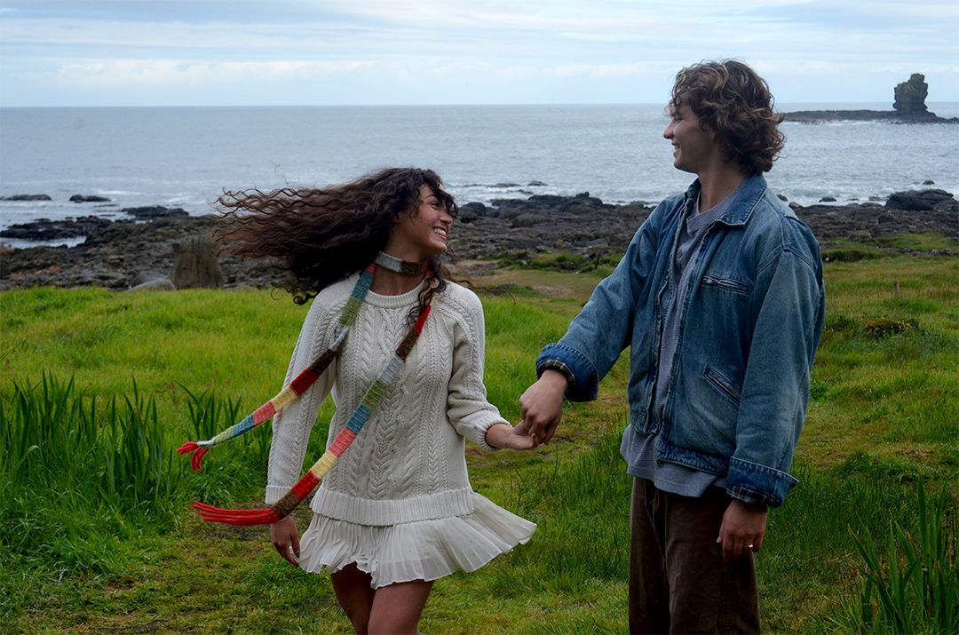 Couple dancing in coastal field with ocean in background.