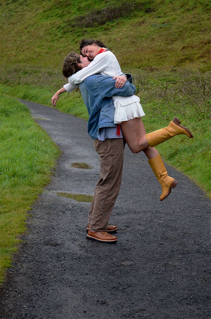 Man lifting woman on rural path in hills.