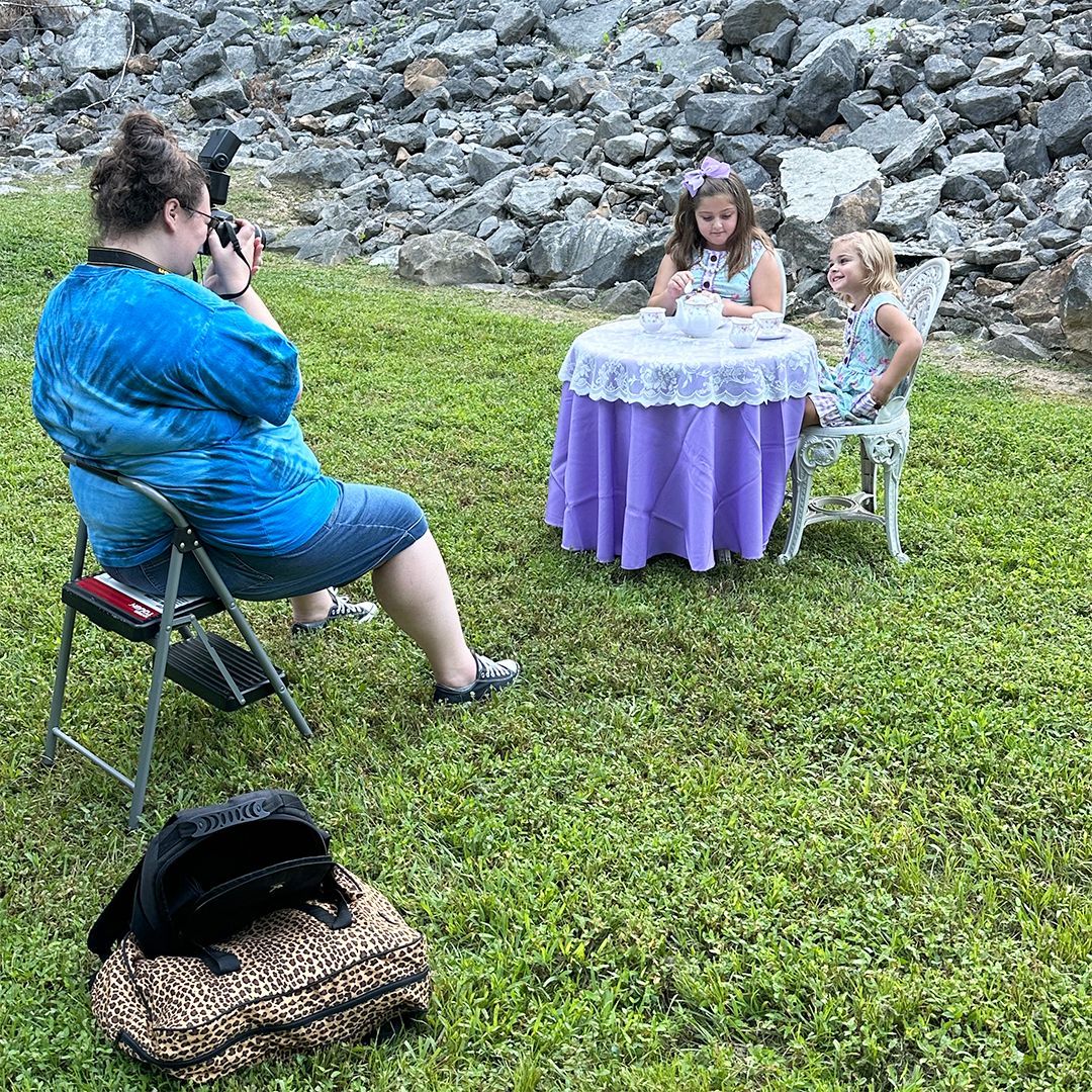 Photographer photographing two young girls outdoors.