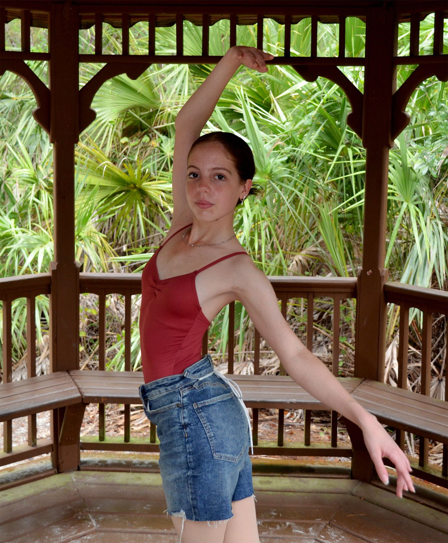 Ballet dancer gracefully posing inside a wooden gazebo.