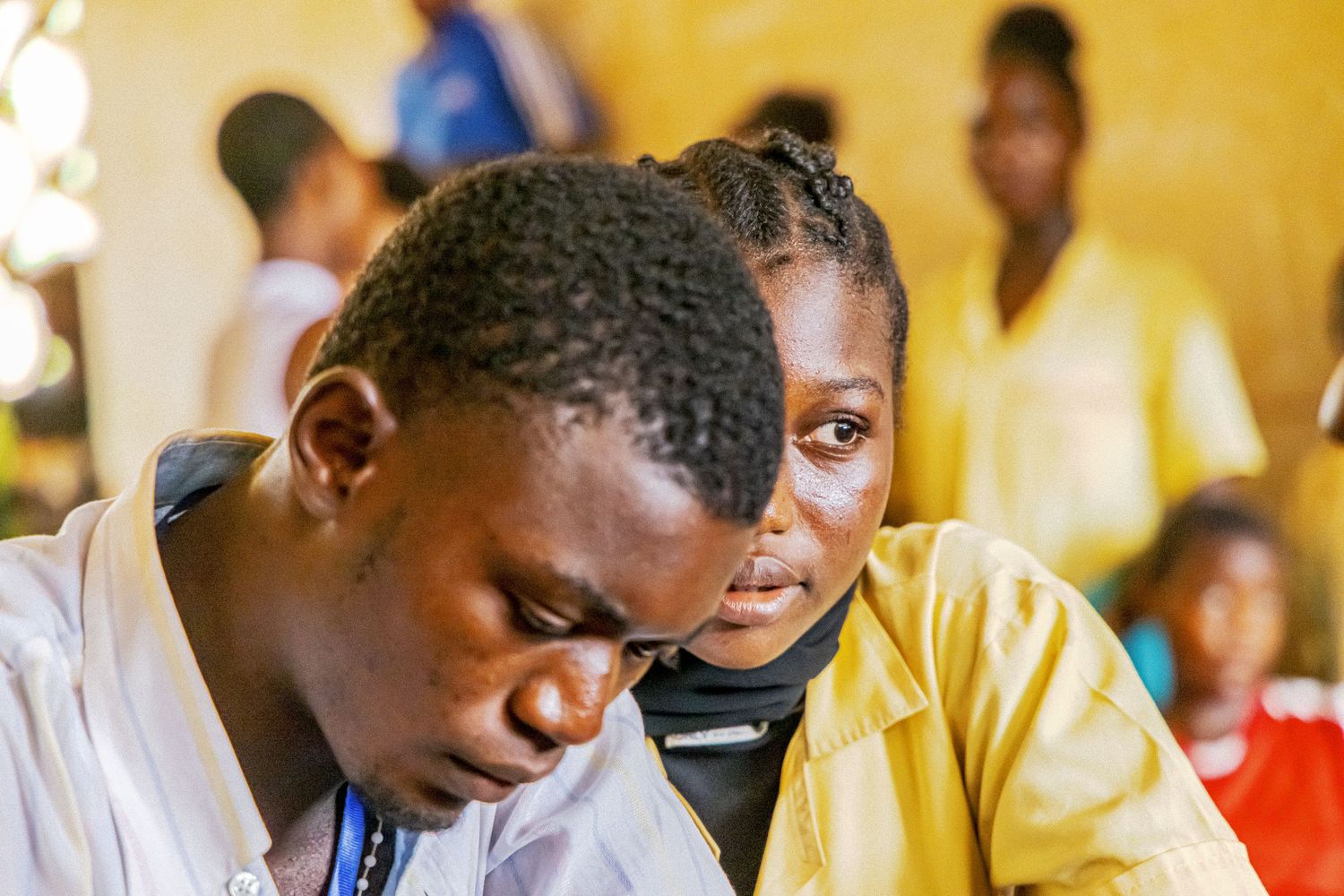 Two African students lean together studying intently in a classroom setting.