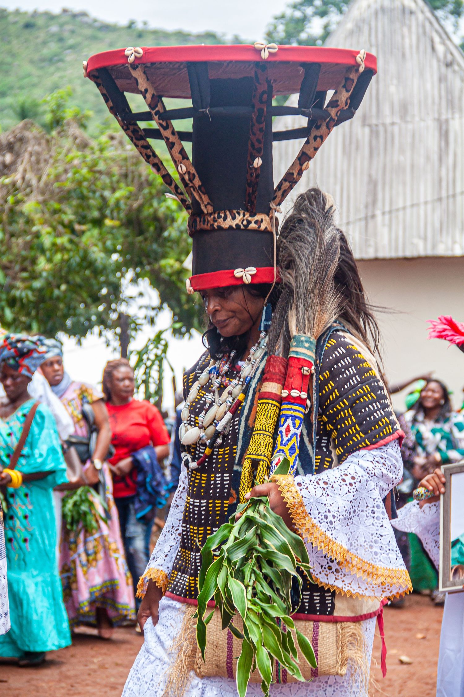 A performer in elaborate traditional African ceremonial costume with large flat headdress dances at a cultural festival.
