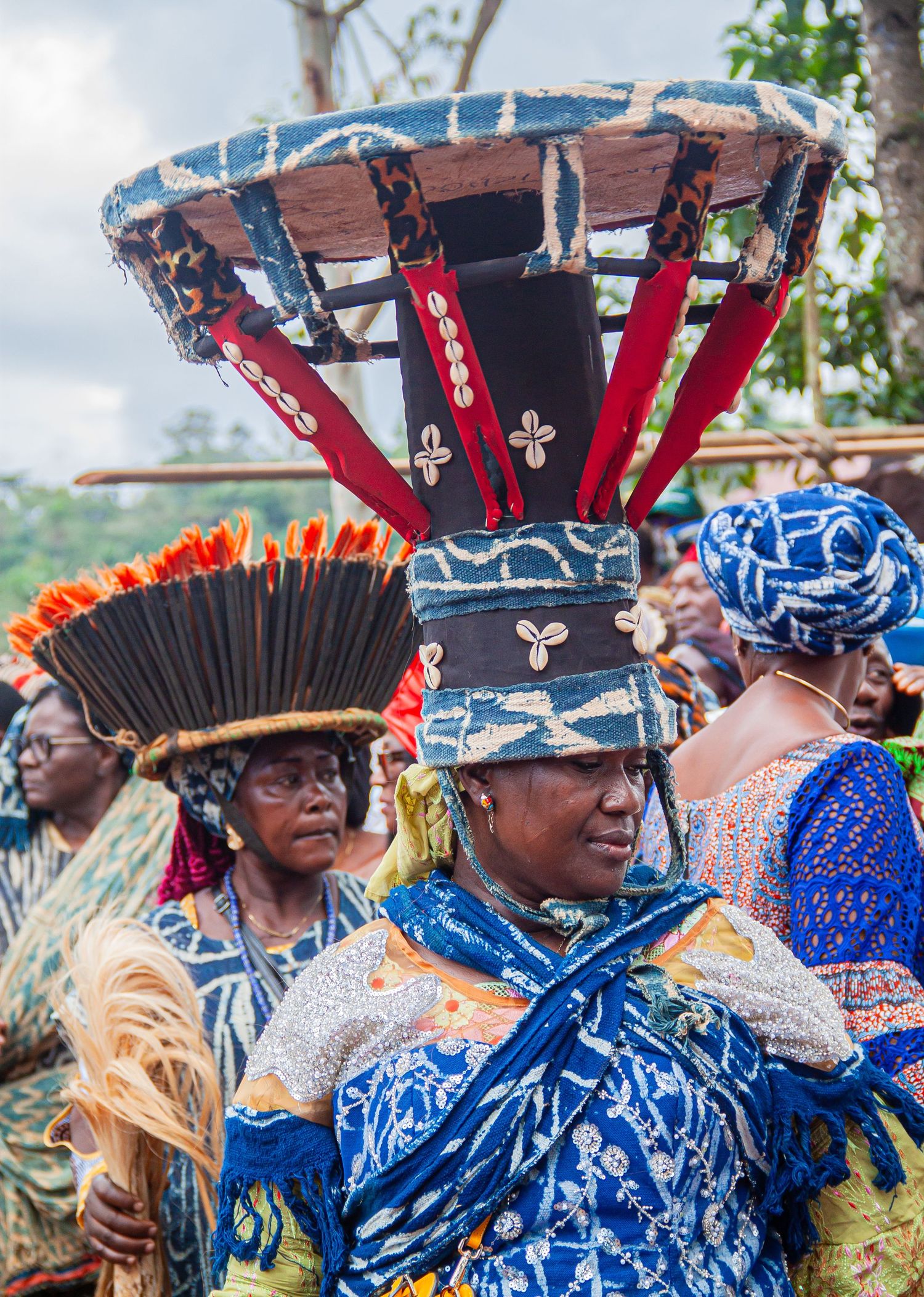 Woman in traditional African ceremonial attire with elaborate headdress at cultural festival.
