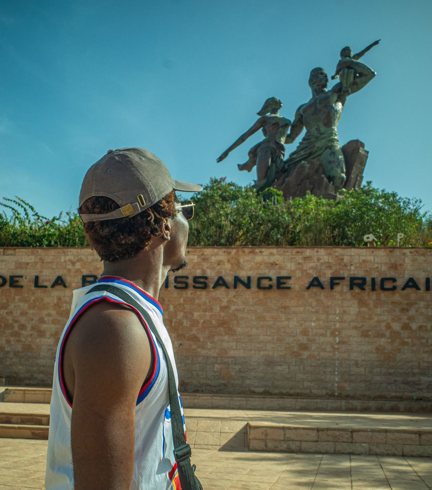 A traveler in a cap views the African Renaissance Monument with its inscription in Dakar, Senegal.