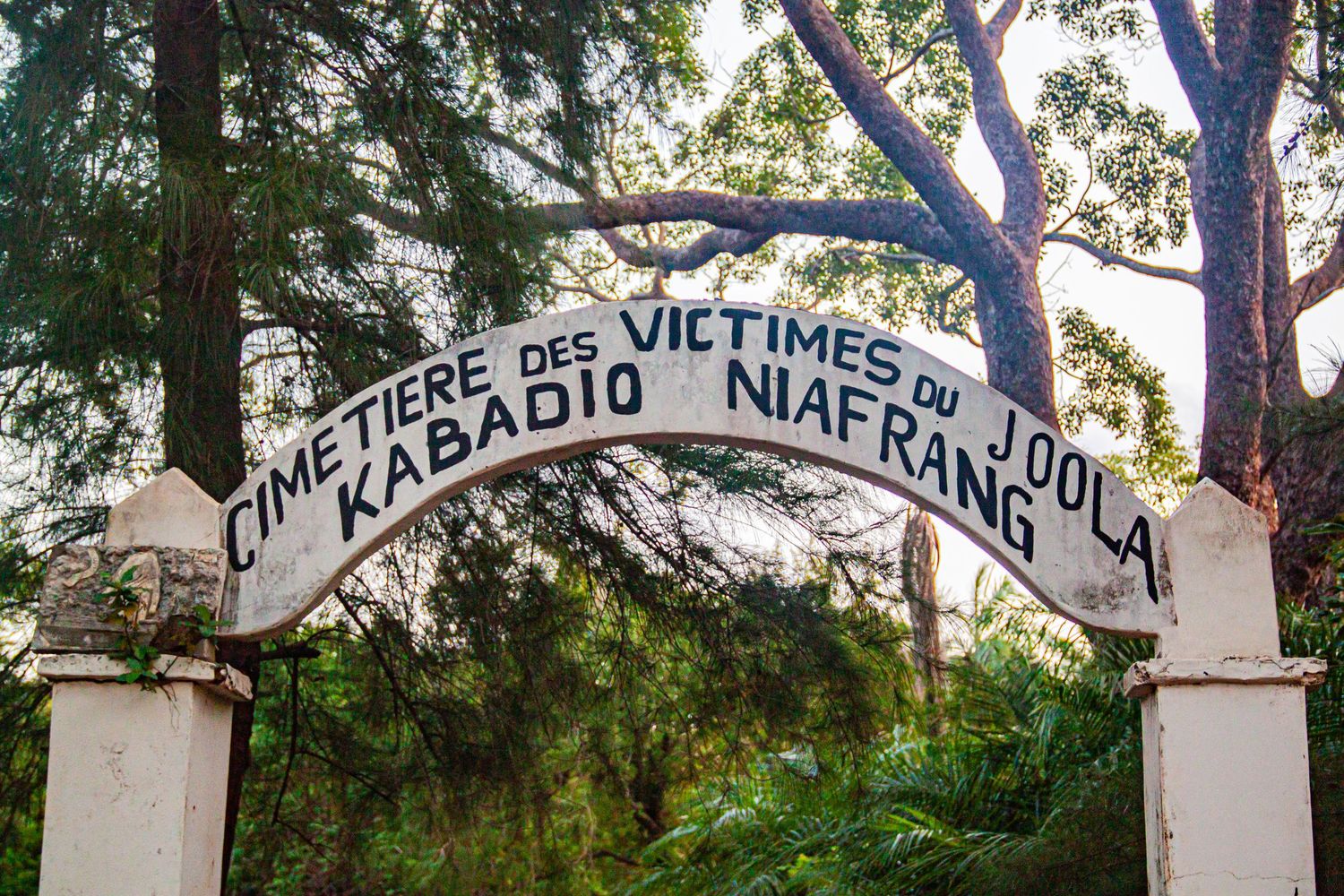 Stone arch gateway reading Cimetiere des Victimes du Joola Kabadio Niafrang in Senegal.
