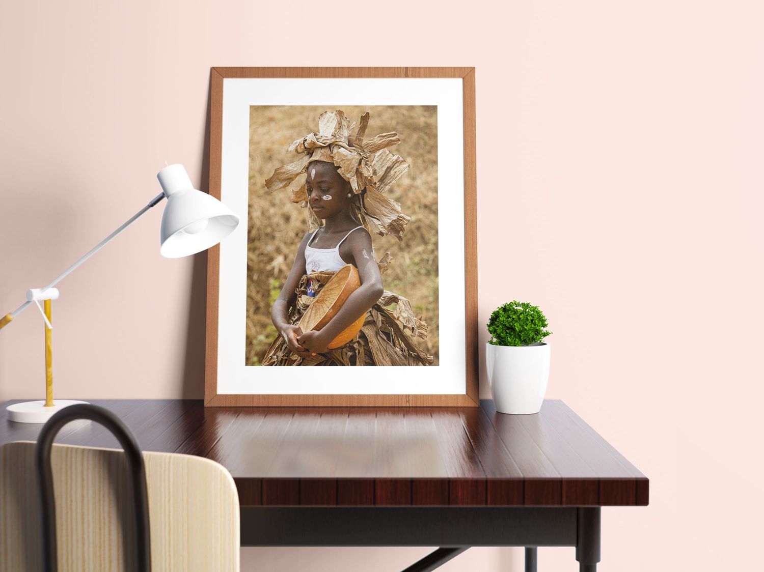 Framed fine art photograph of a traditionally dressed African woman carrying a basket on a desk.