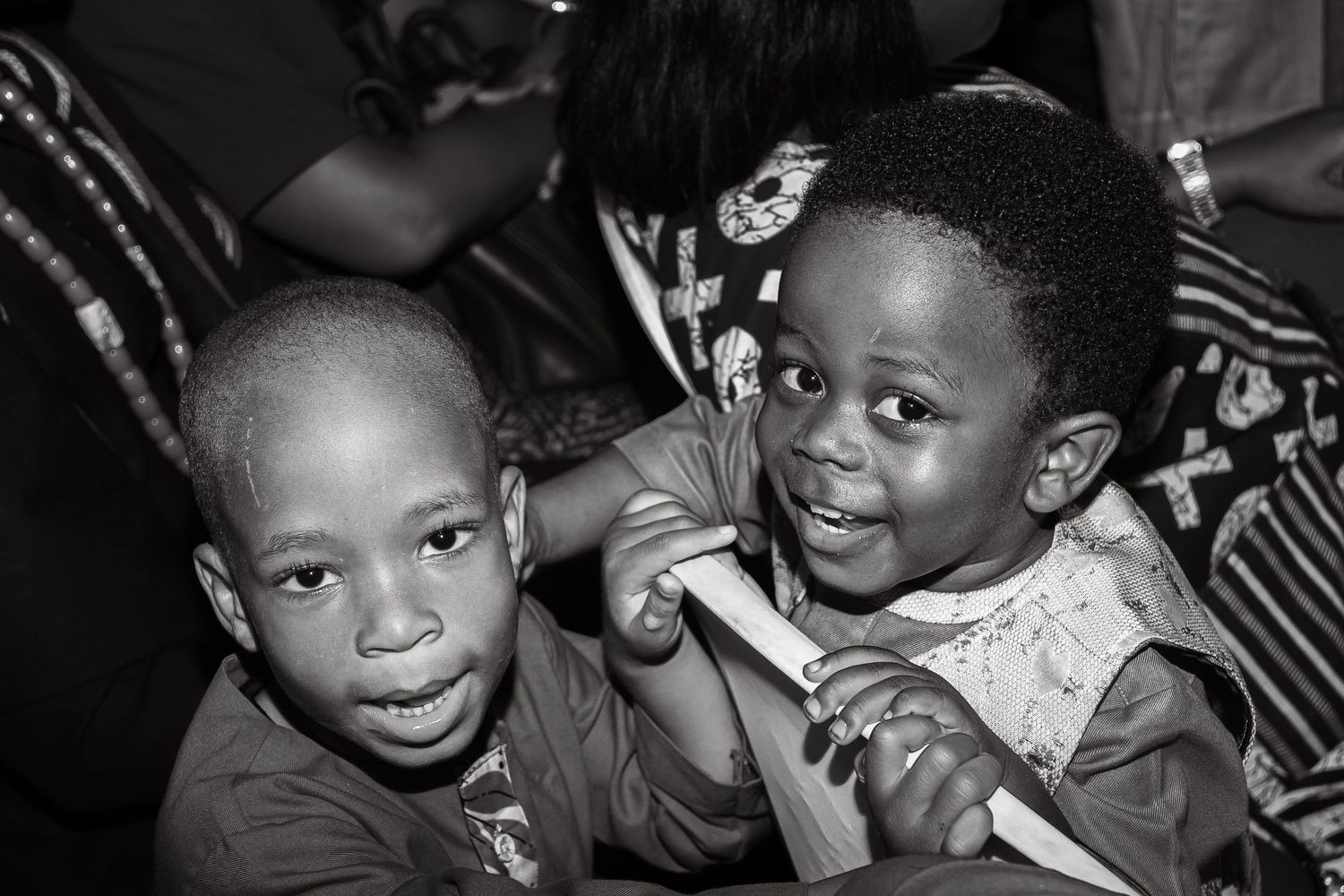 Two young African children smiling and posing together in a black and white photo.
